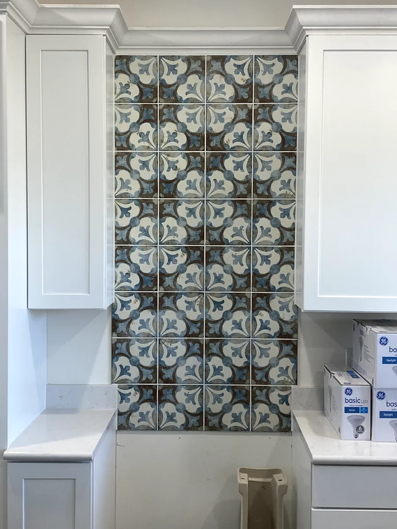 White kitchen with blue patterned tile backsplash between cabinets.