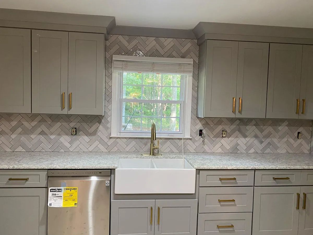 Kitchen with gray cabinets, a white sink, and patterned backsplash.