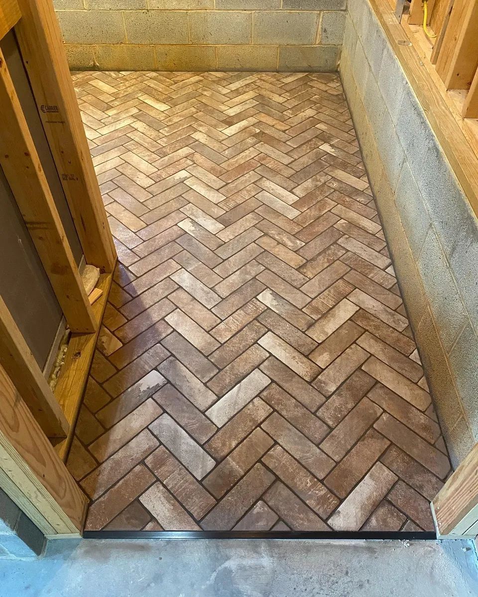 Herringbone brick floor in a doorway, framed by wooden and concrete walls.