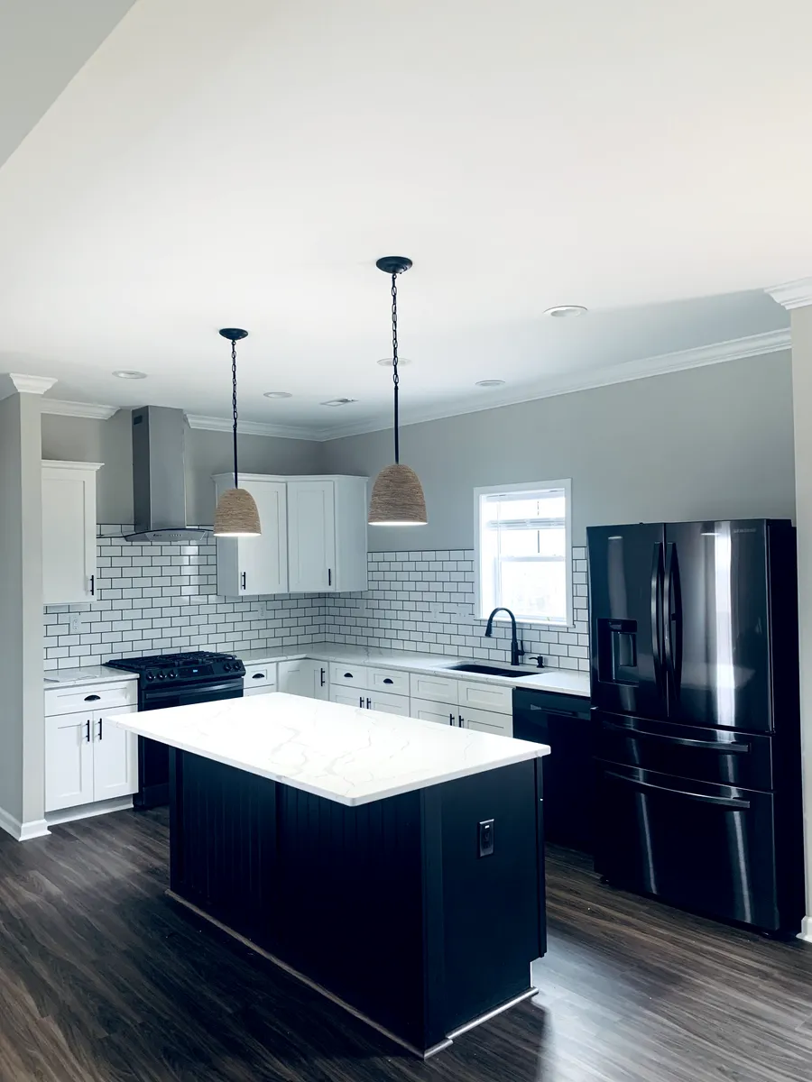 Modern kitchen with dark island, white countertops, and black appliances.
