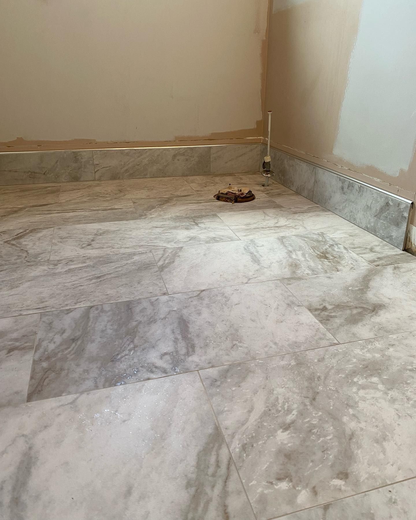 Marble tiled floor and baseboards in a room with unfinished walls.