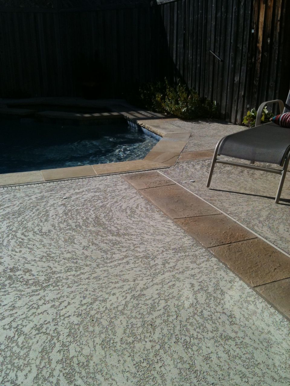 A patio with a chair and a swimming pool