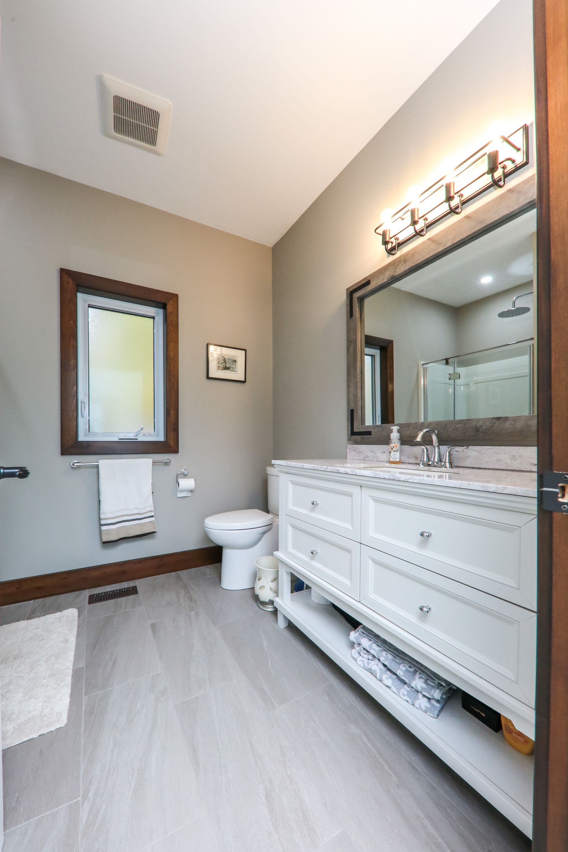 A bathroom with a toilet , sink and mirror.