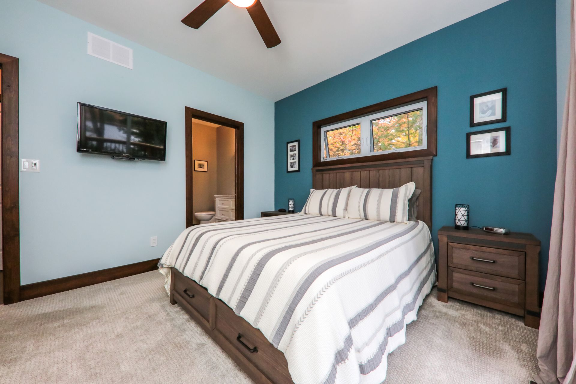 A bedroom with a king size bed , nightstand , television and ceiling fan.