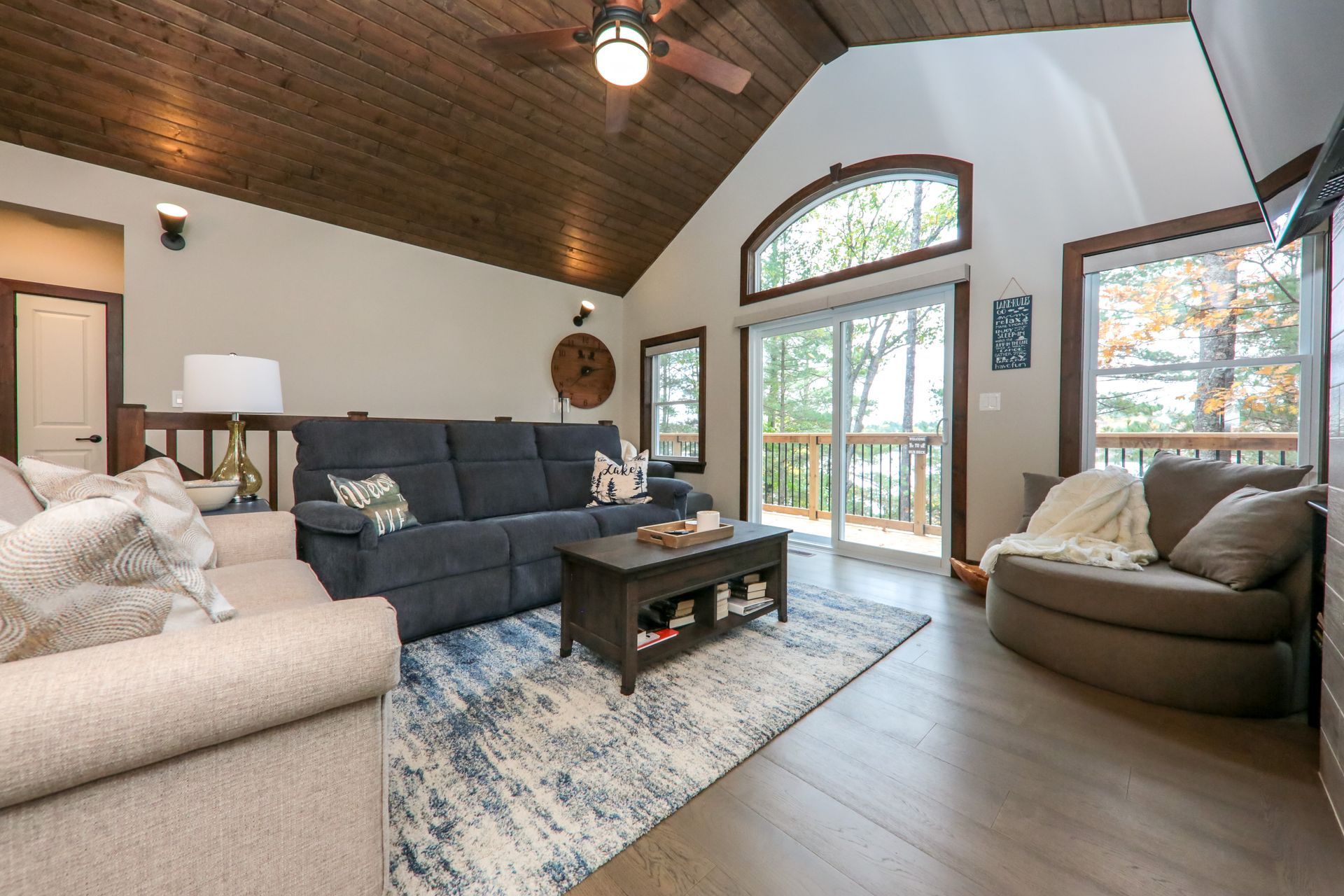 A living room with a couch , chair , coffee table and ceiling fan.