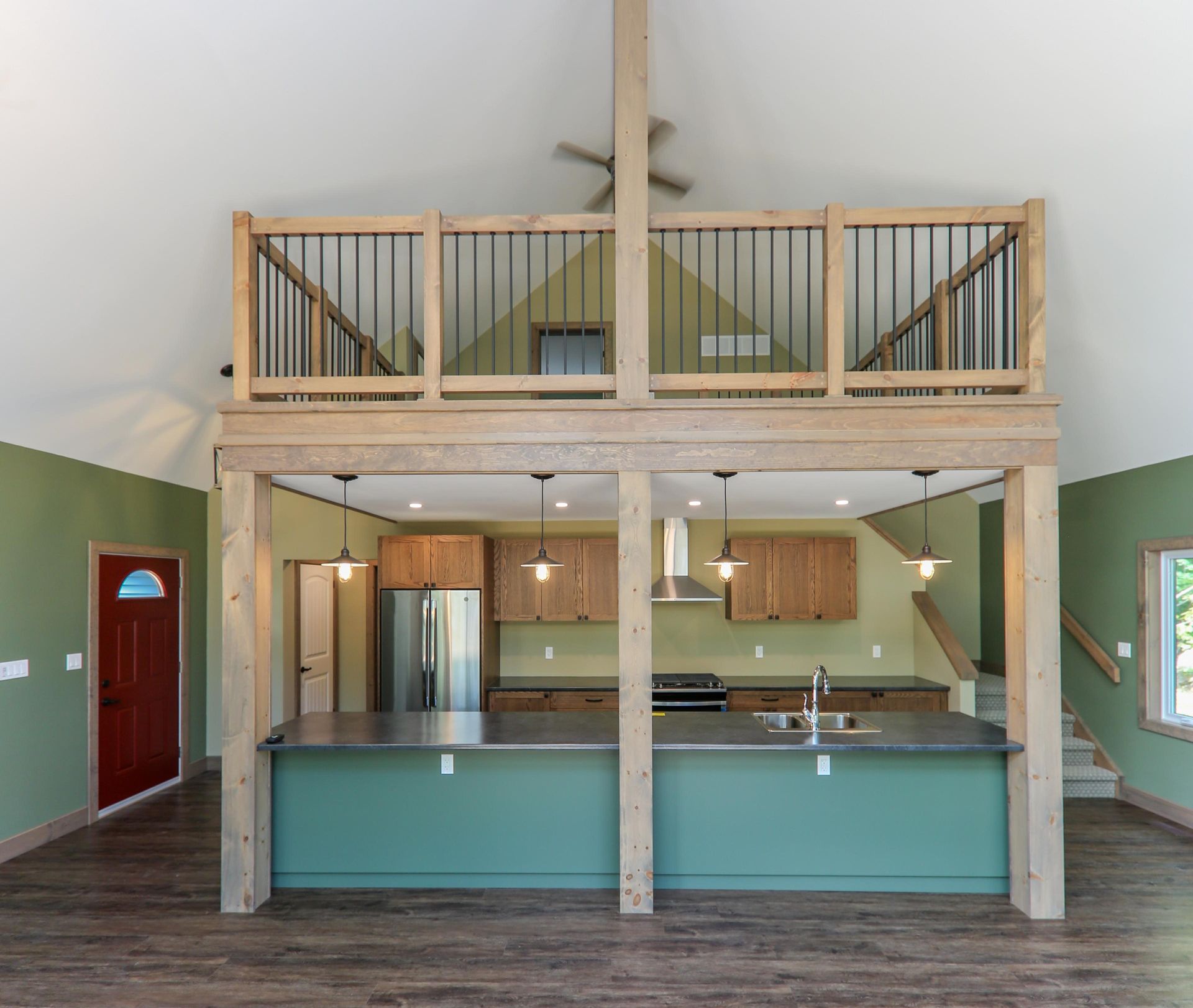 A kitchen with green cabinets and a balcony above it