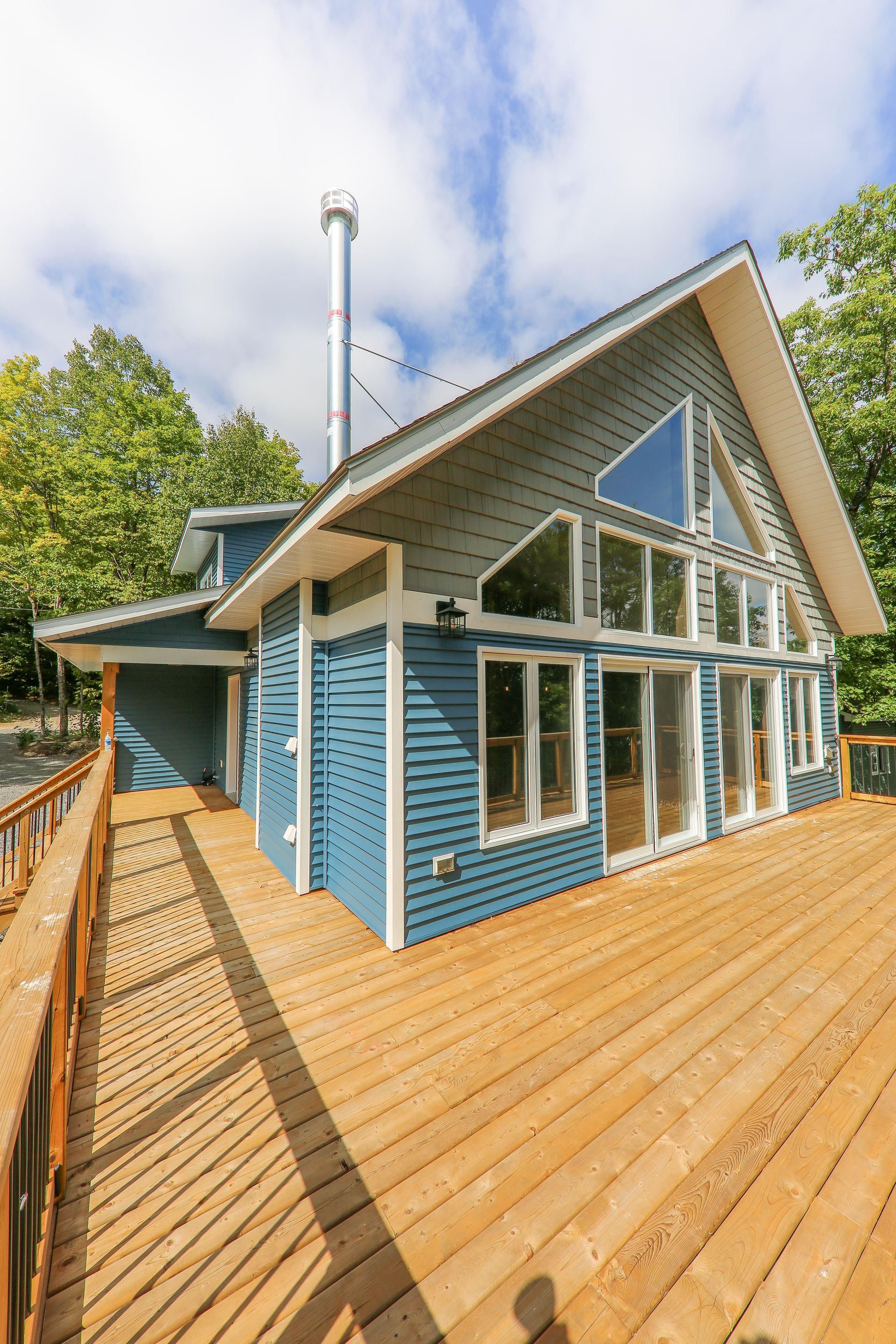 A large blue house with a wooden deck in front of it.