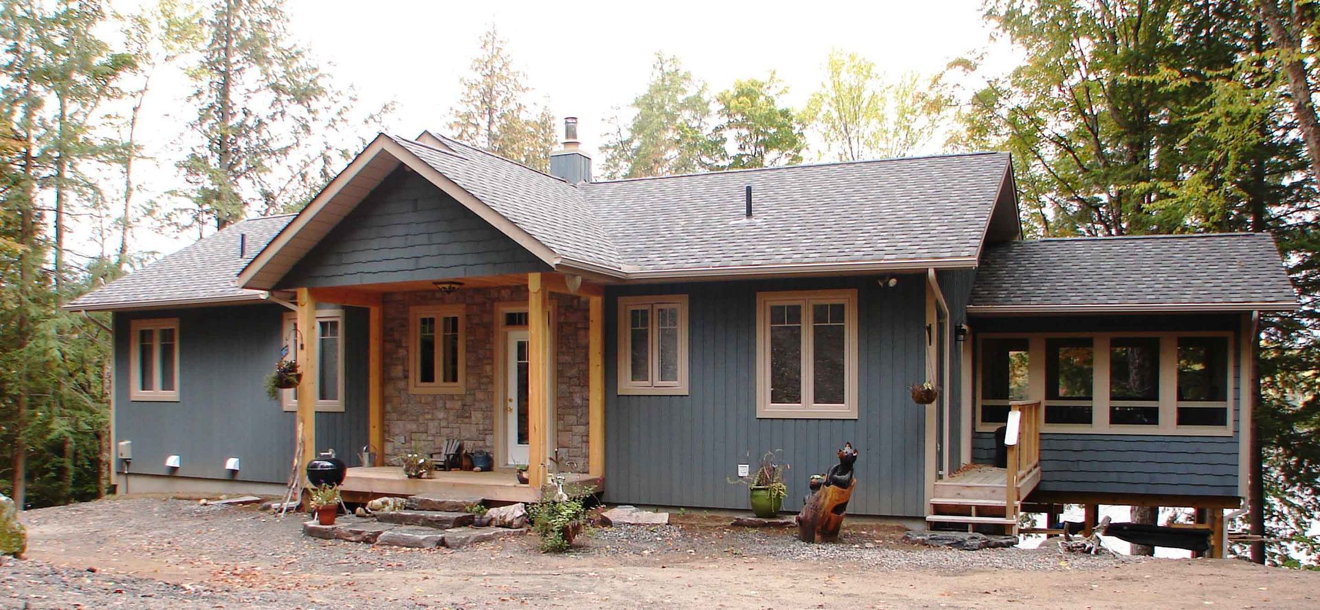 A blue house with a gray roof and a porch