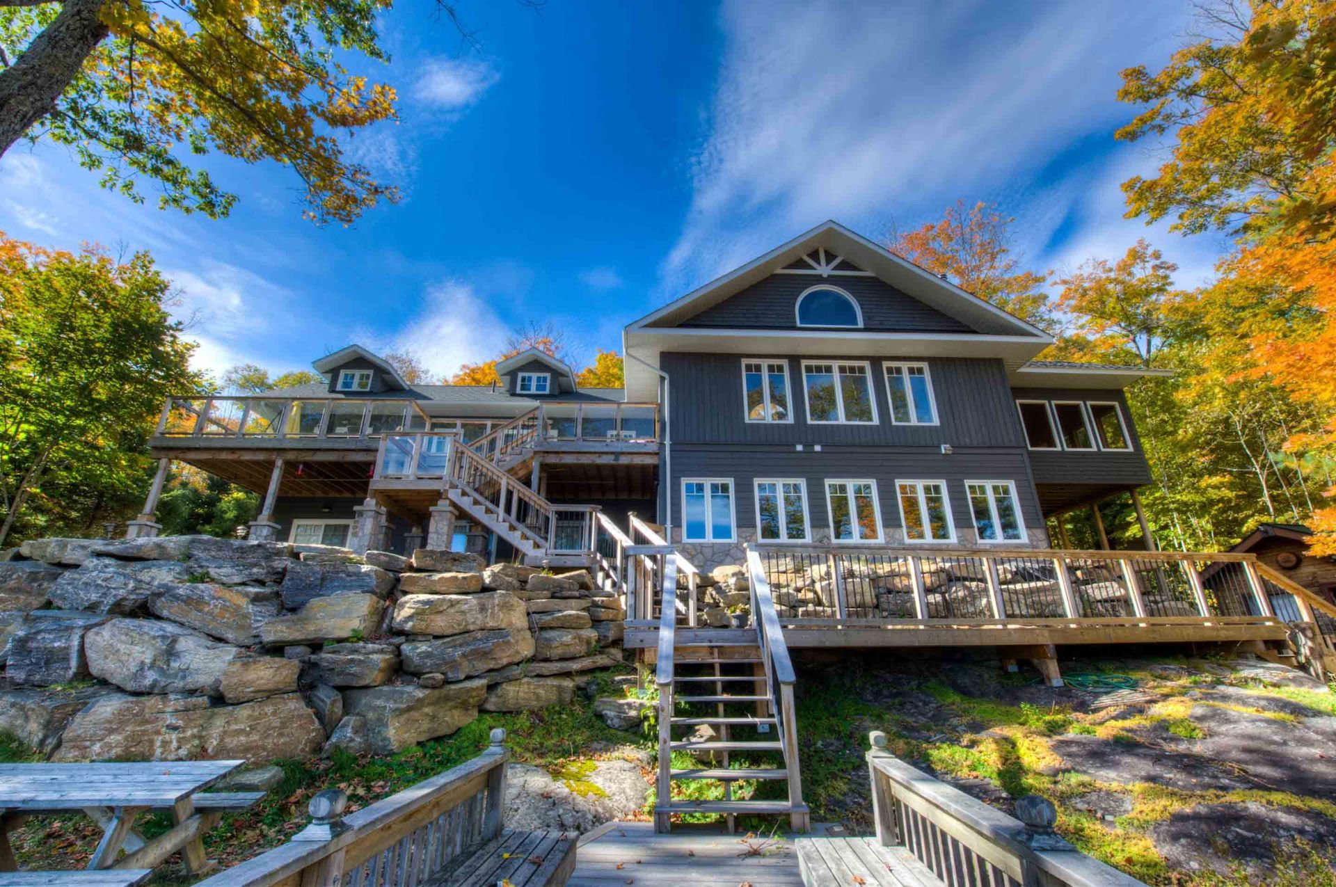 A large house with stairs leading up to it is surrounded by trees.