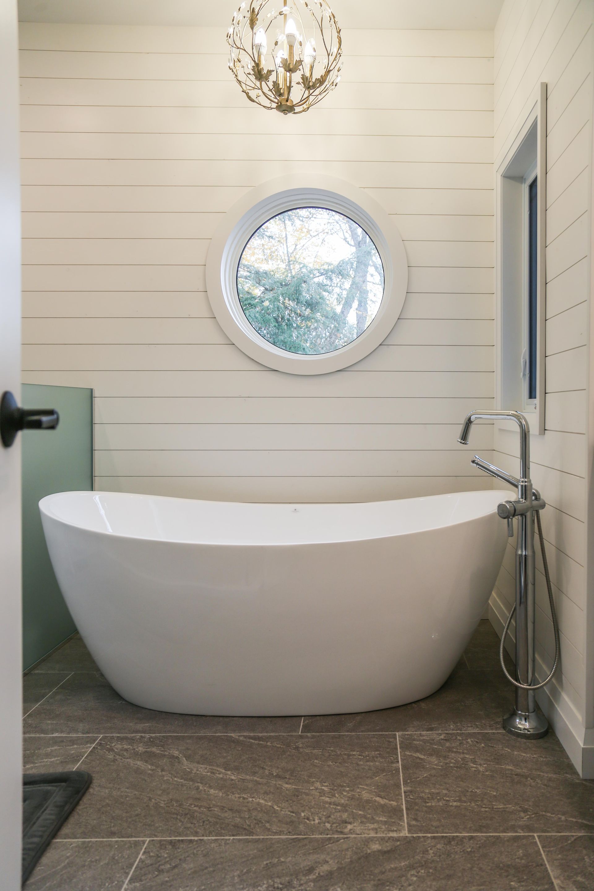 A bathroom with a bathtub and a round window.