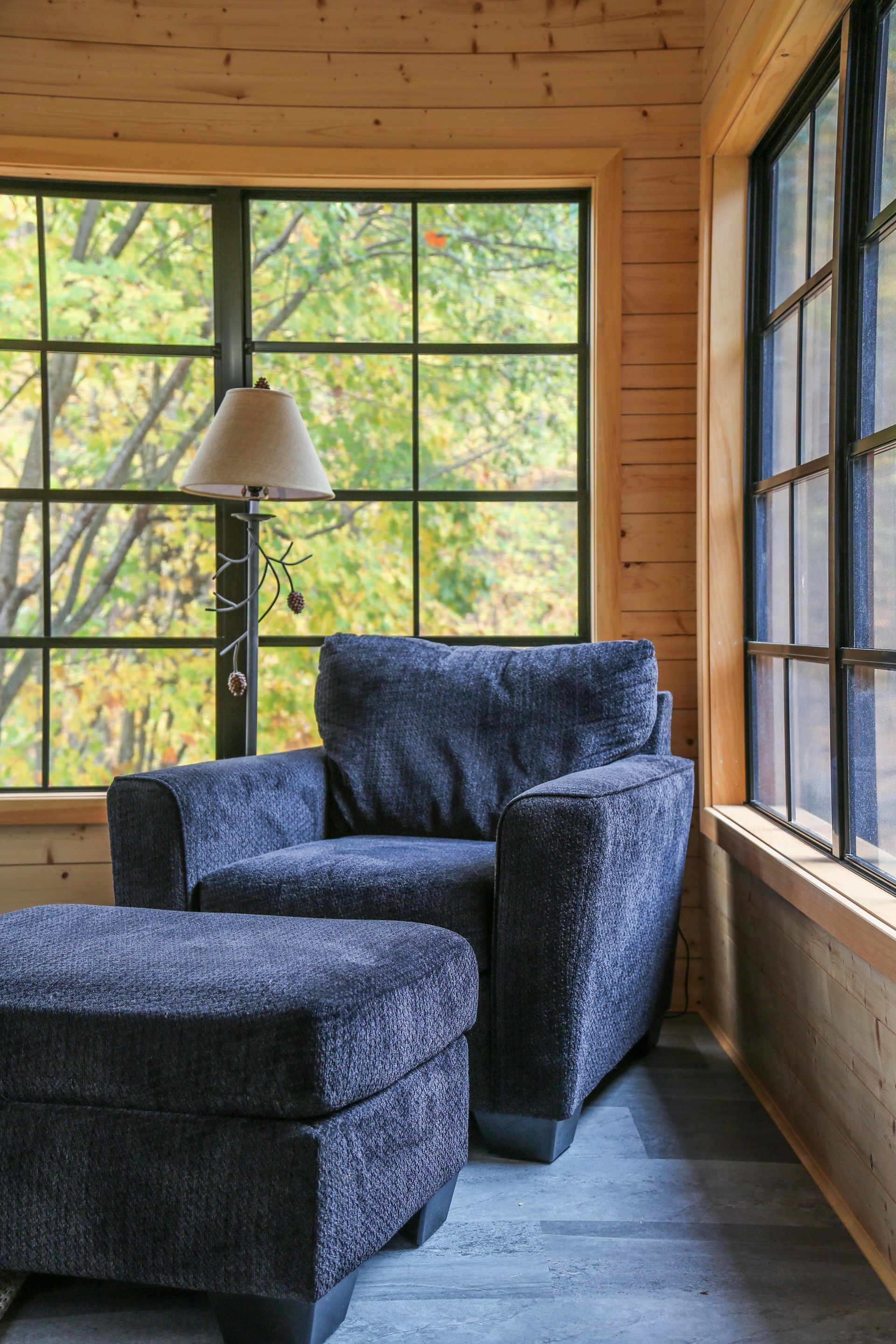 A chair and ottoman are sitting in front of a window in a room.