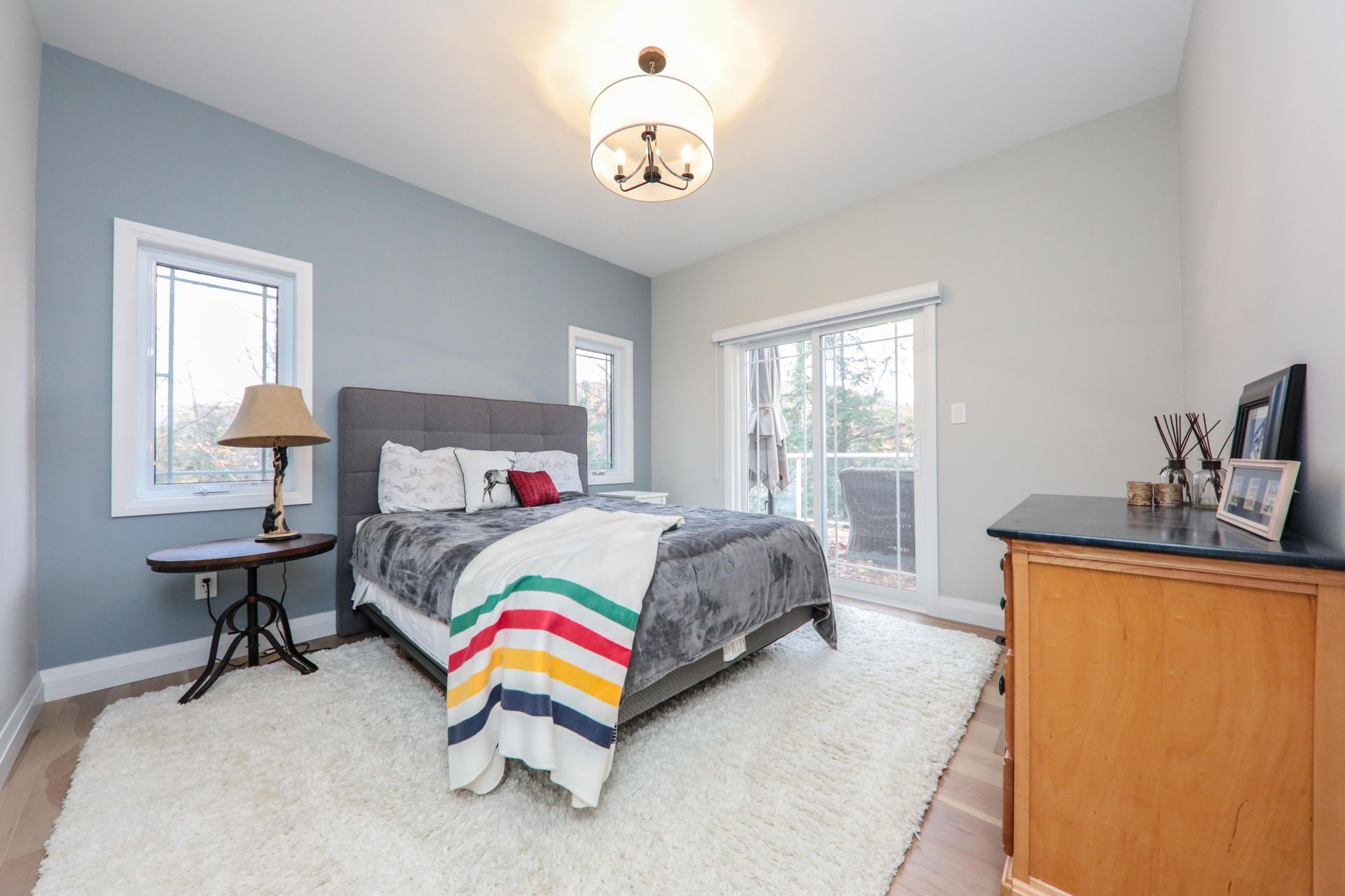 A bedroom with a bed , dresser , lamp and rug.