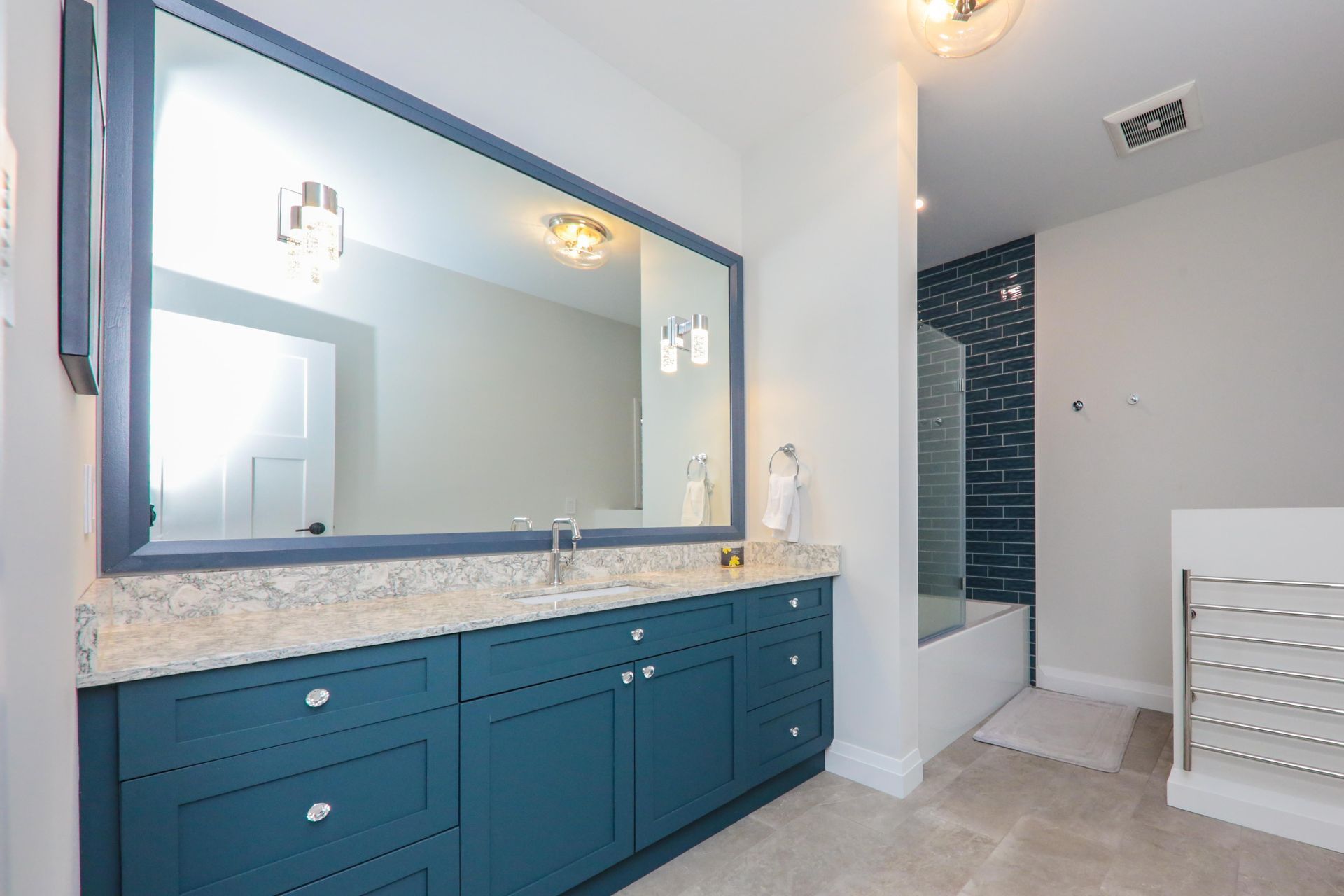 A bathroom with blue cabinets and a large mirror.