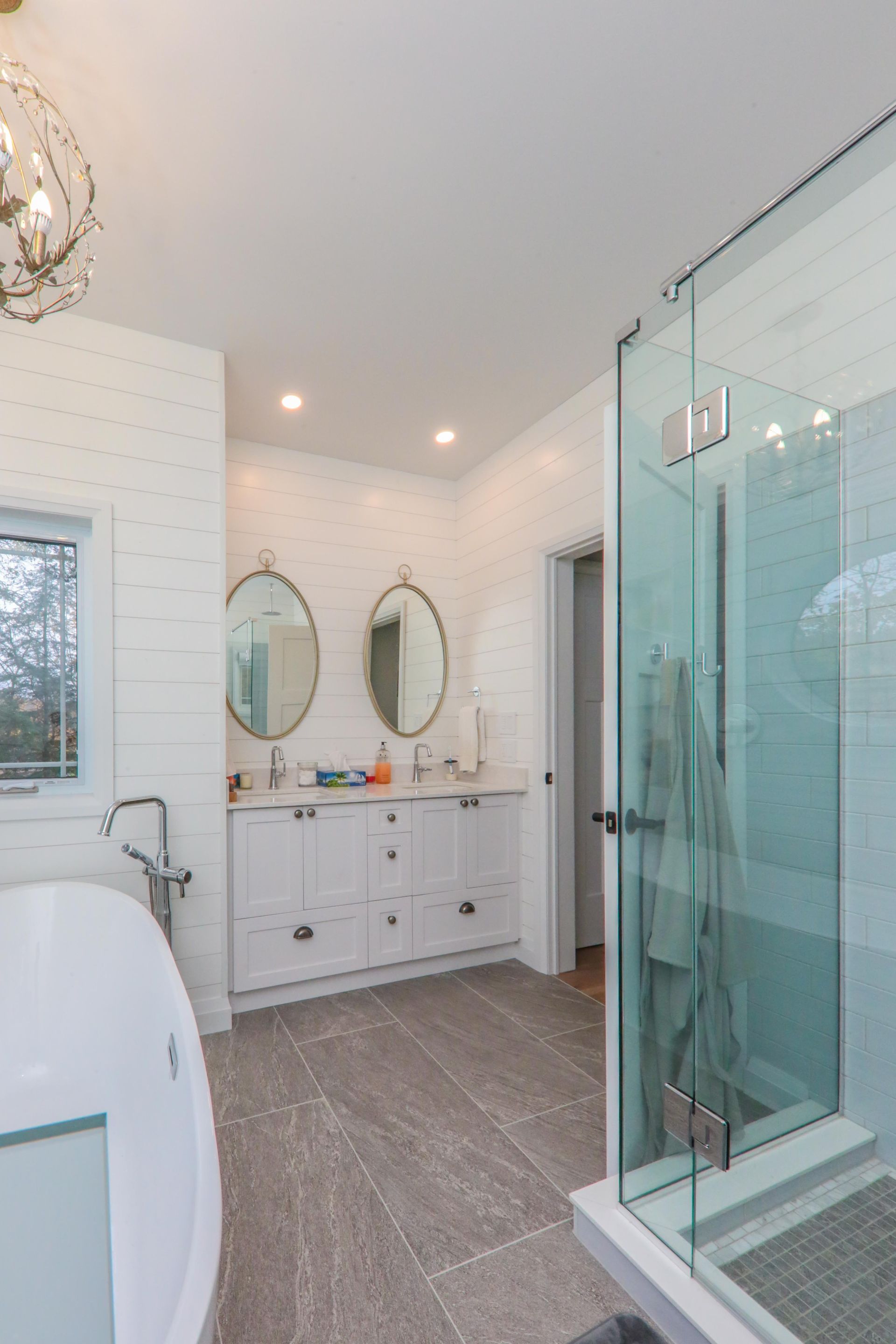 A bathroom with a tub , sink , mirrors and a walk in shower.