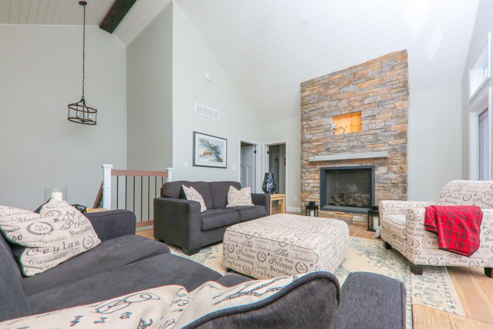 A living room with a couch , chairs , ottoman and fireplace.