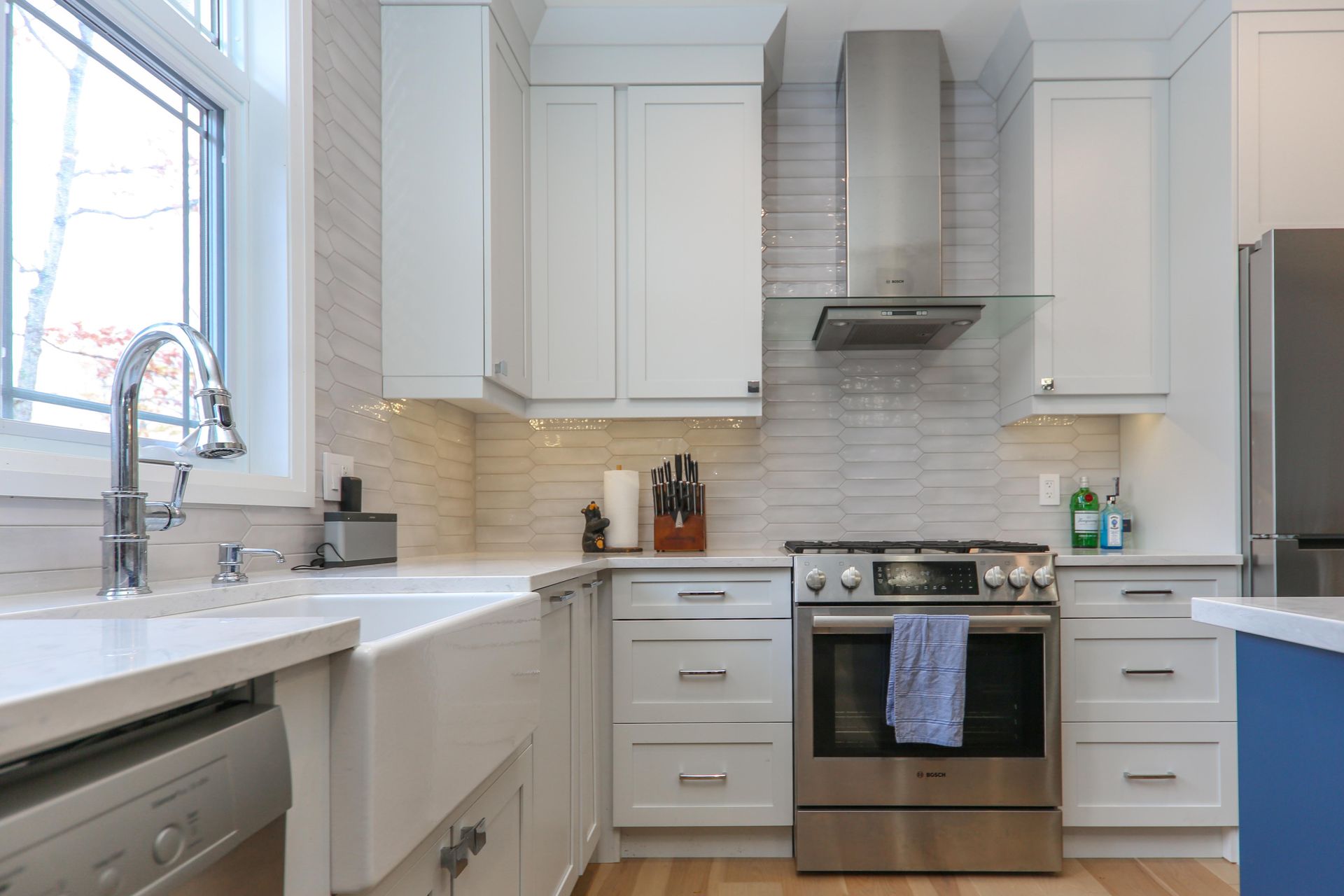 A kitchen with white cabinets , stainless steel appliances , a sink and a window.