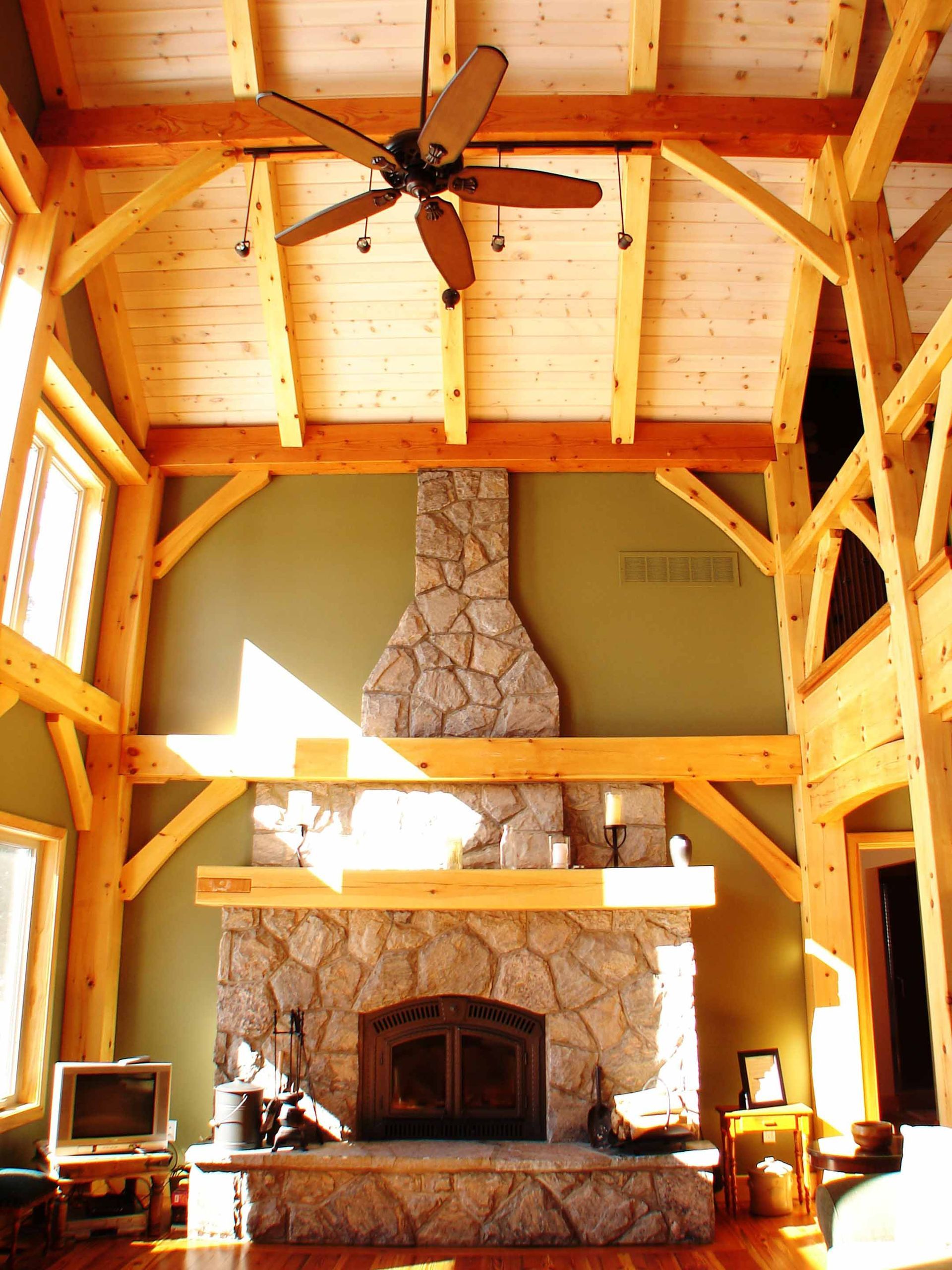 A living room with a stone fireplace and a ceiling fan