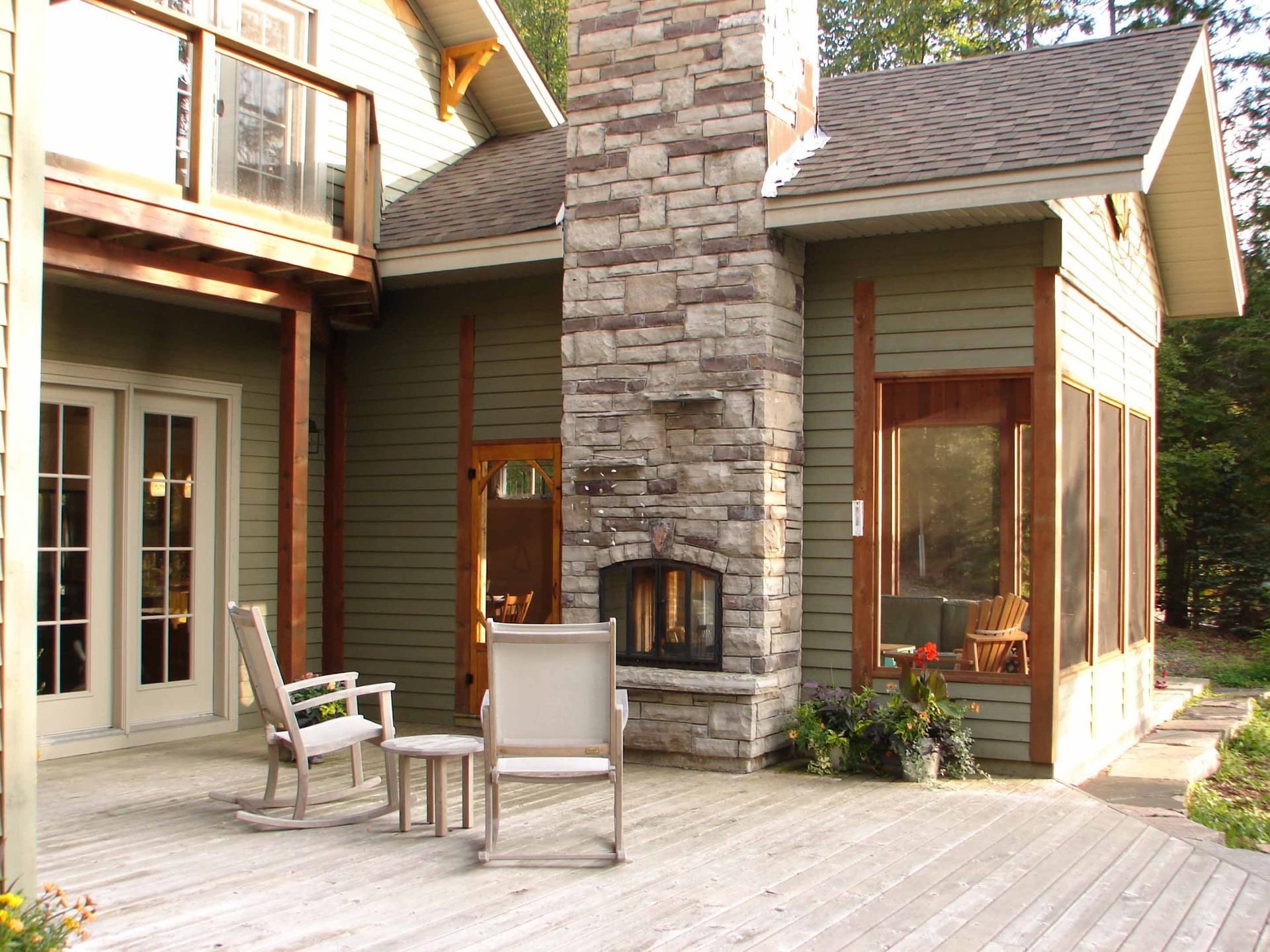 A house with a stone fireplace and rocking chairs on the deck