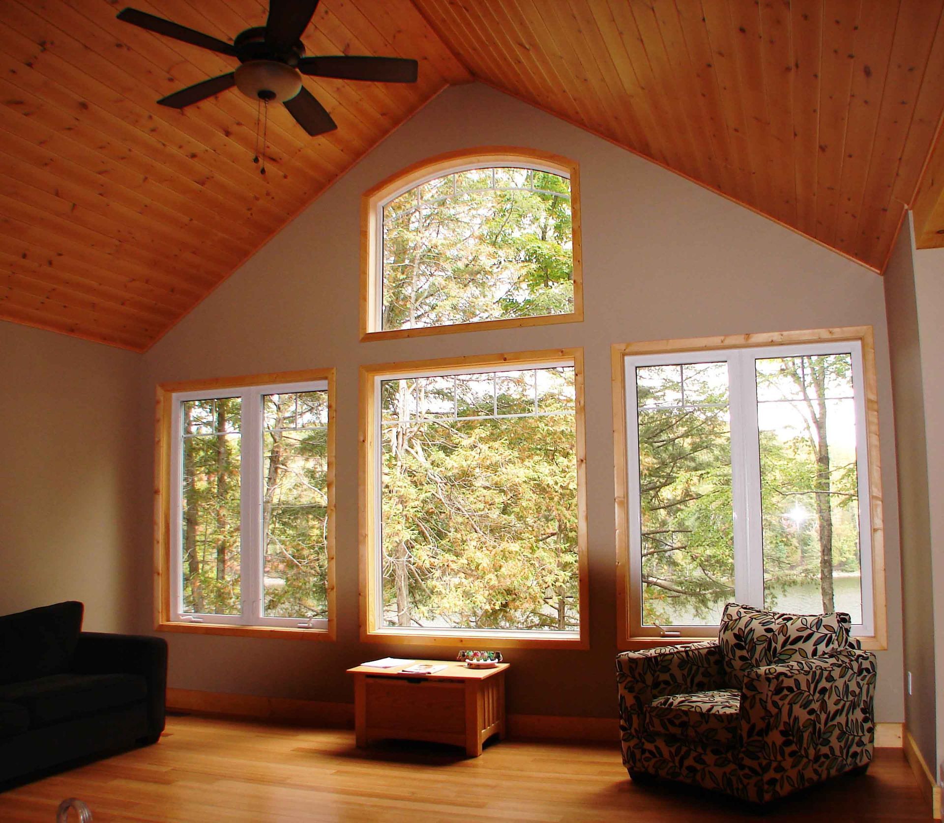 A living room with a ceiling fan and lots of windows