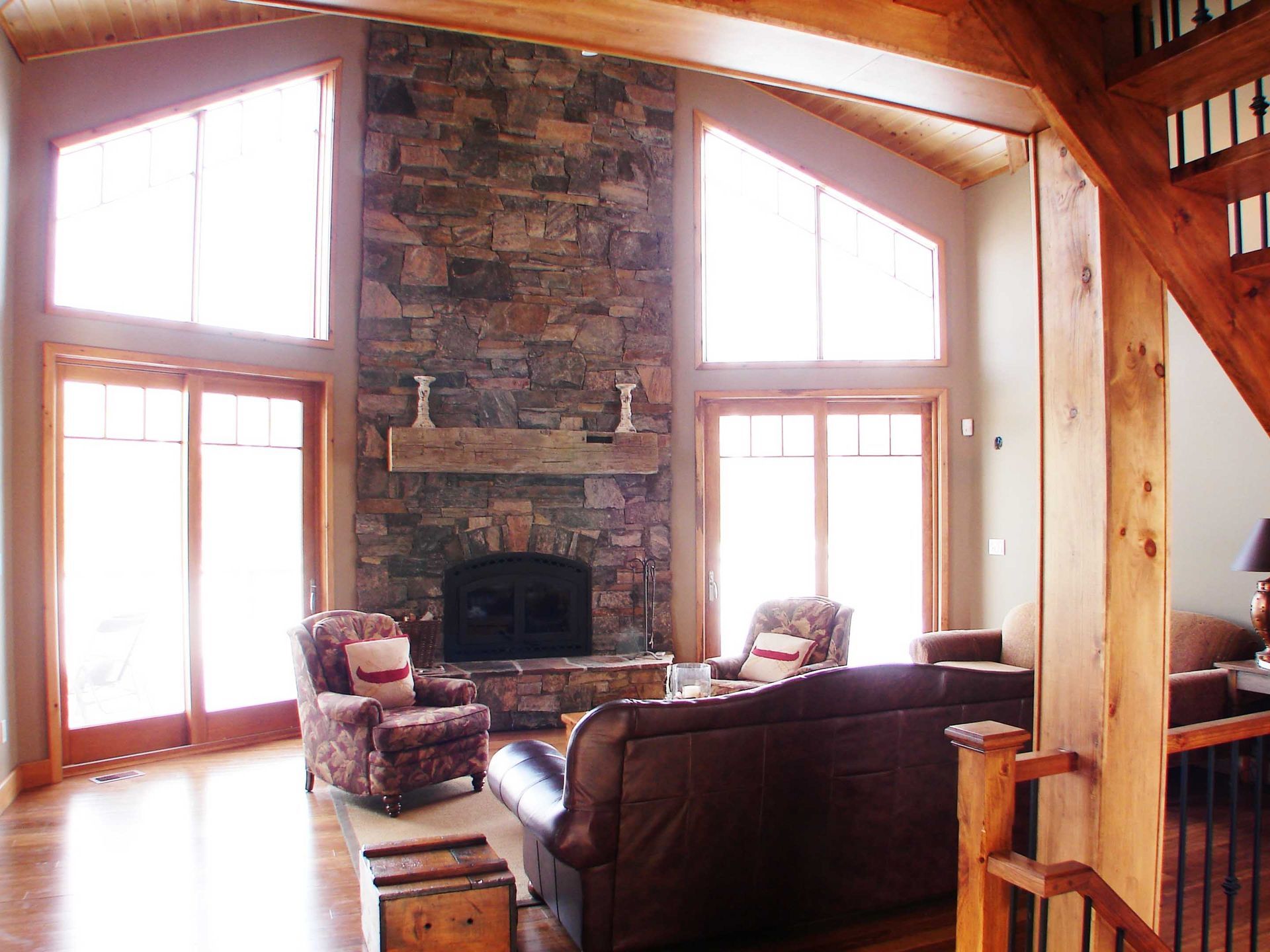 A living room with a stone fireplace and lots of windows