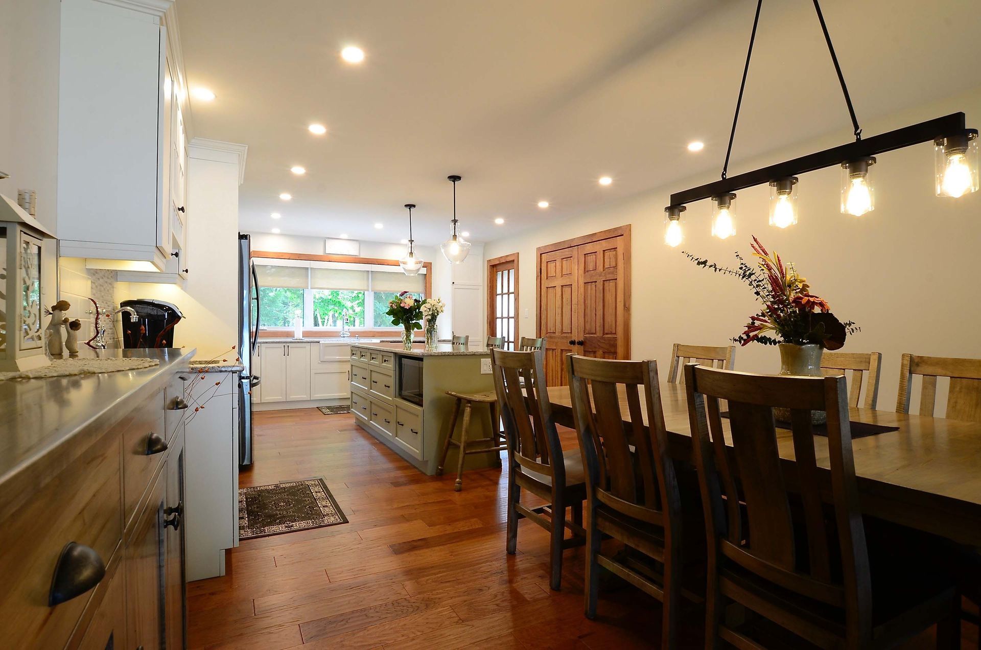 A kitchen with a dining table and chairs and a chandelier hanging from the ceiling.