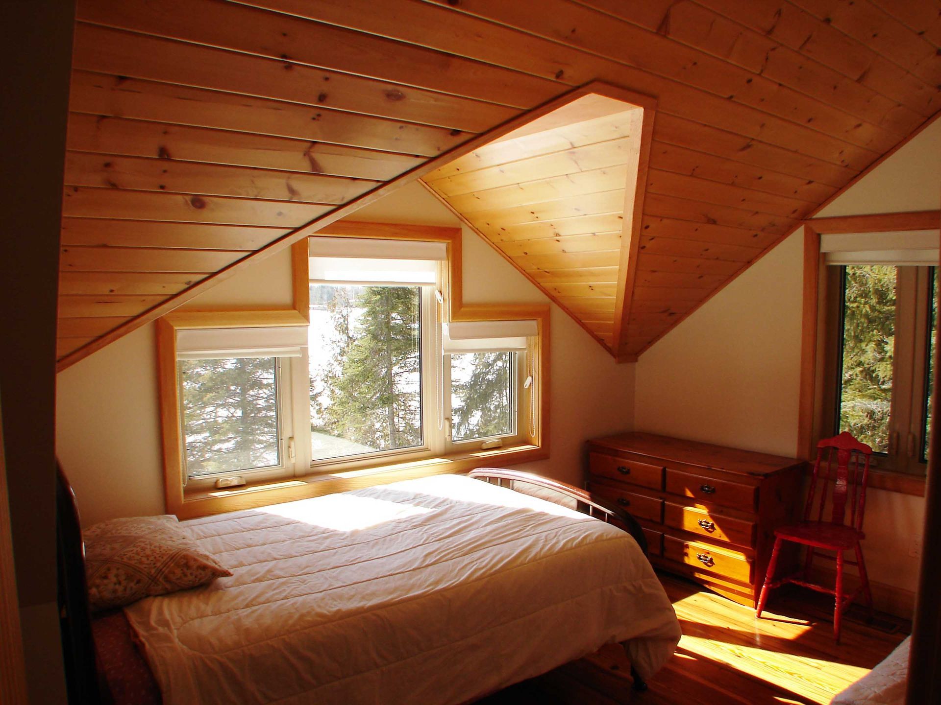 A bedroom with a slanted ceiling and a bed