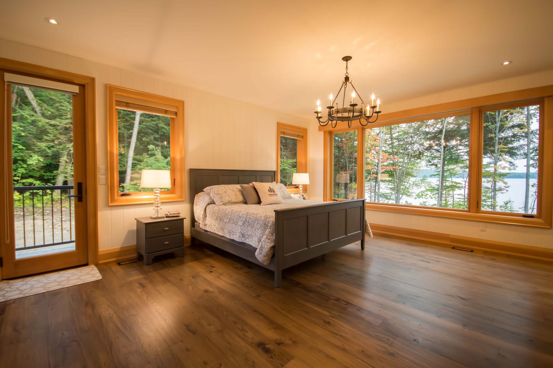 There is a large bed in the middle of the room with a lot of windows.