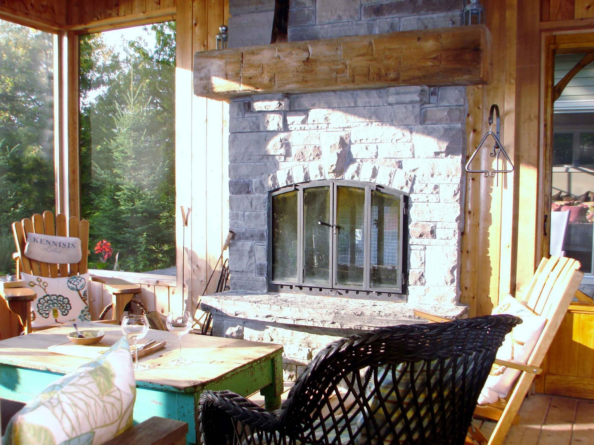 A screened in porch with a fireplace and chairs