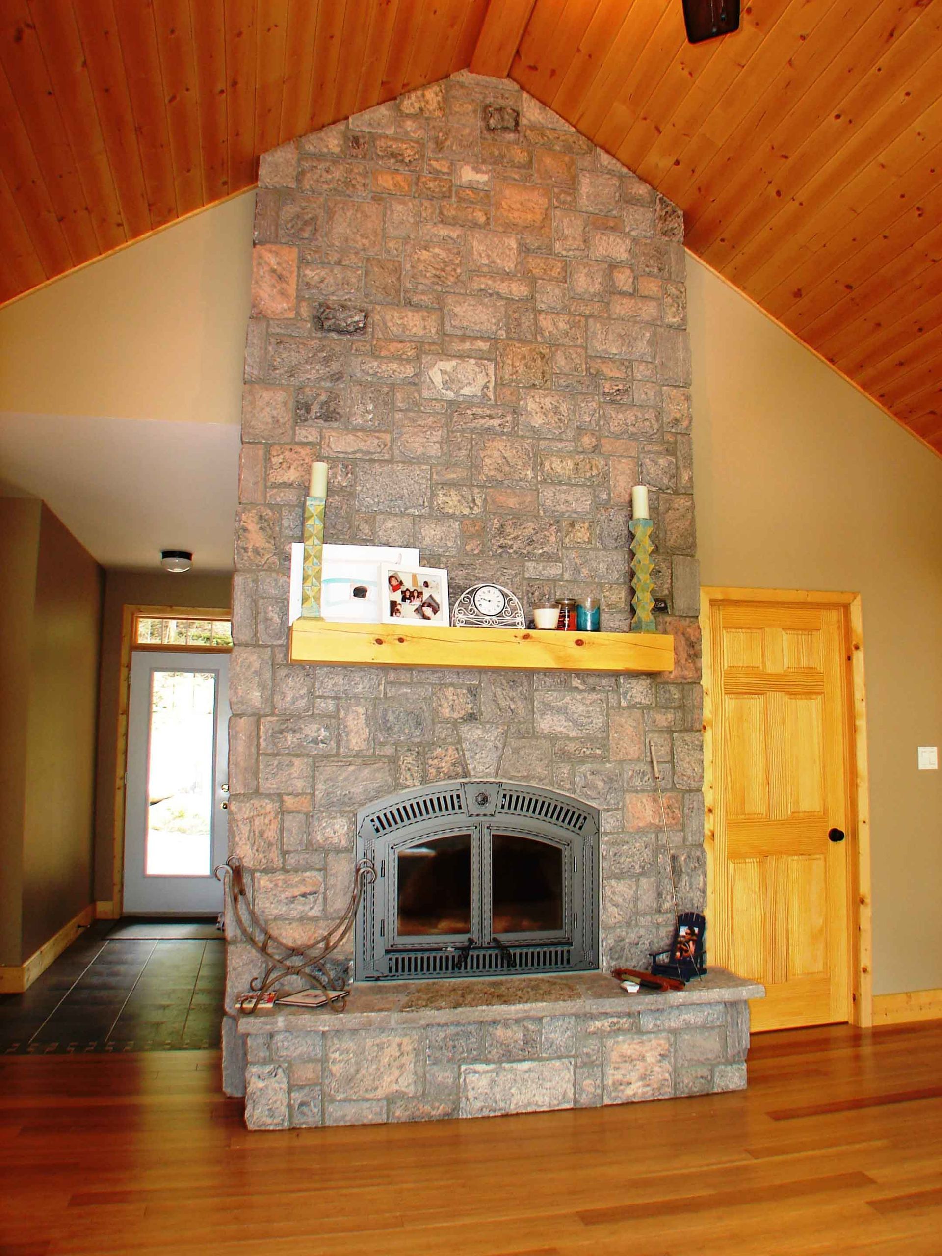 A stone fireplace with a wooden mantle in a living room