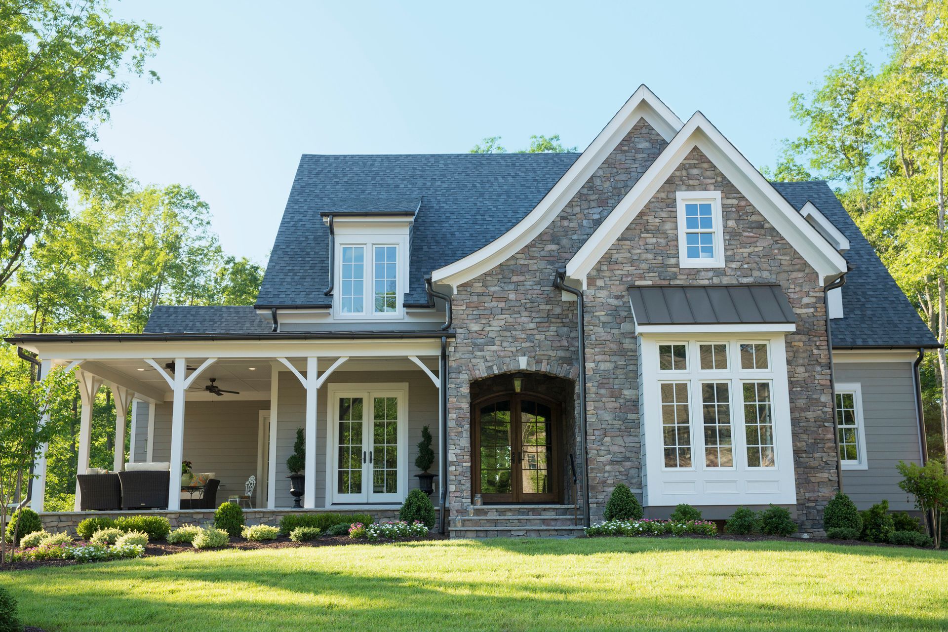 A custom home with a large front porch and spacious yard, perfect for outdoor living.