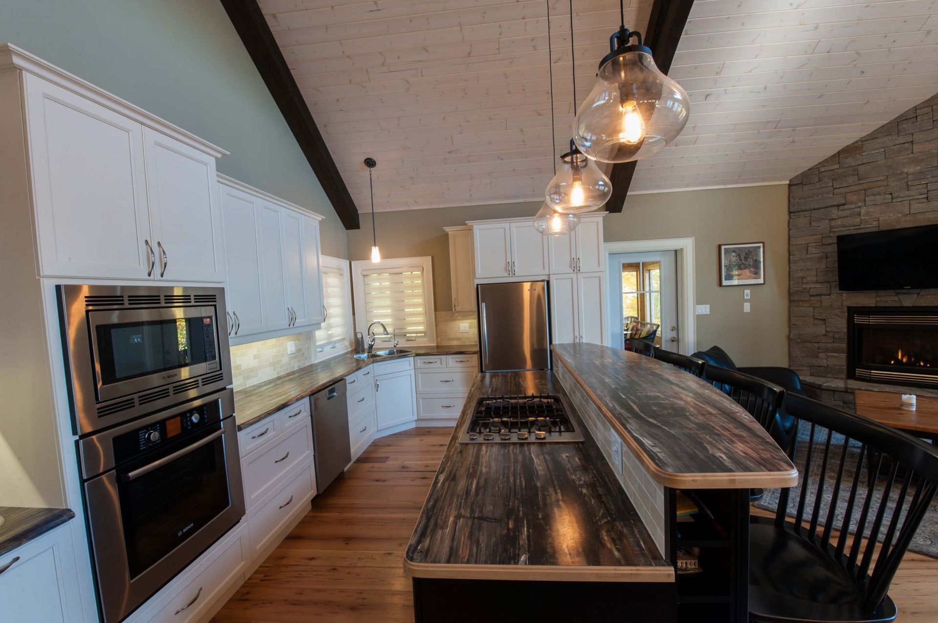 A kitchen with white cabinets , stainless steel appliances , a large island and a fireplace.