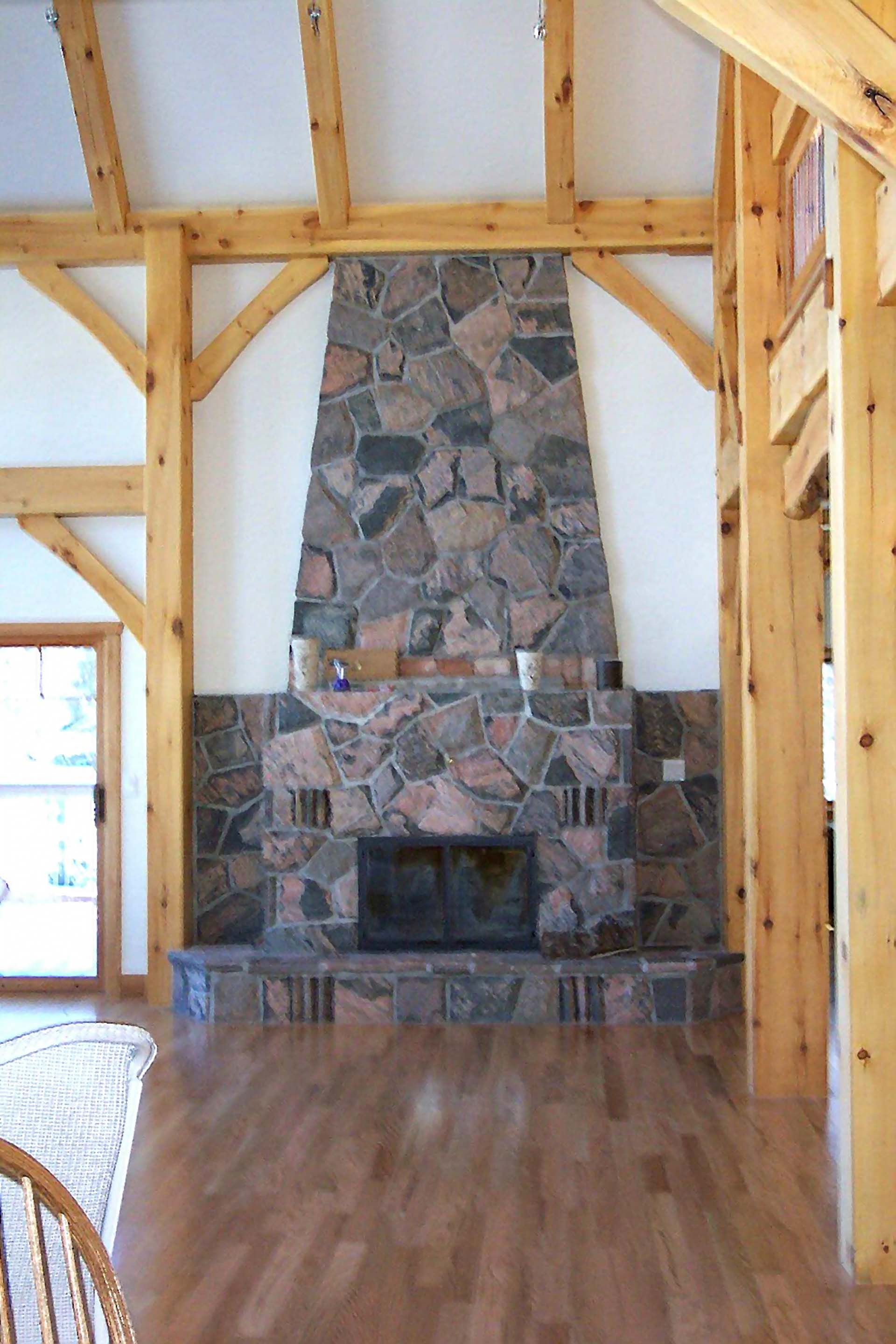 A living room with a stone fireplace and wooden beams
