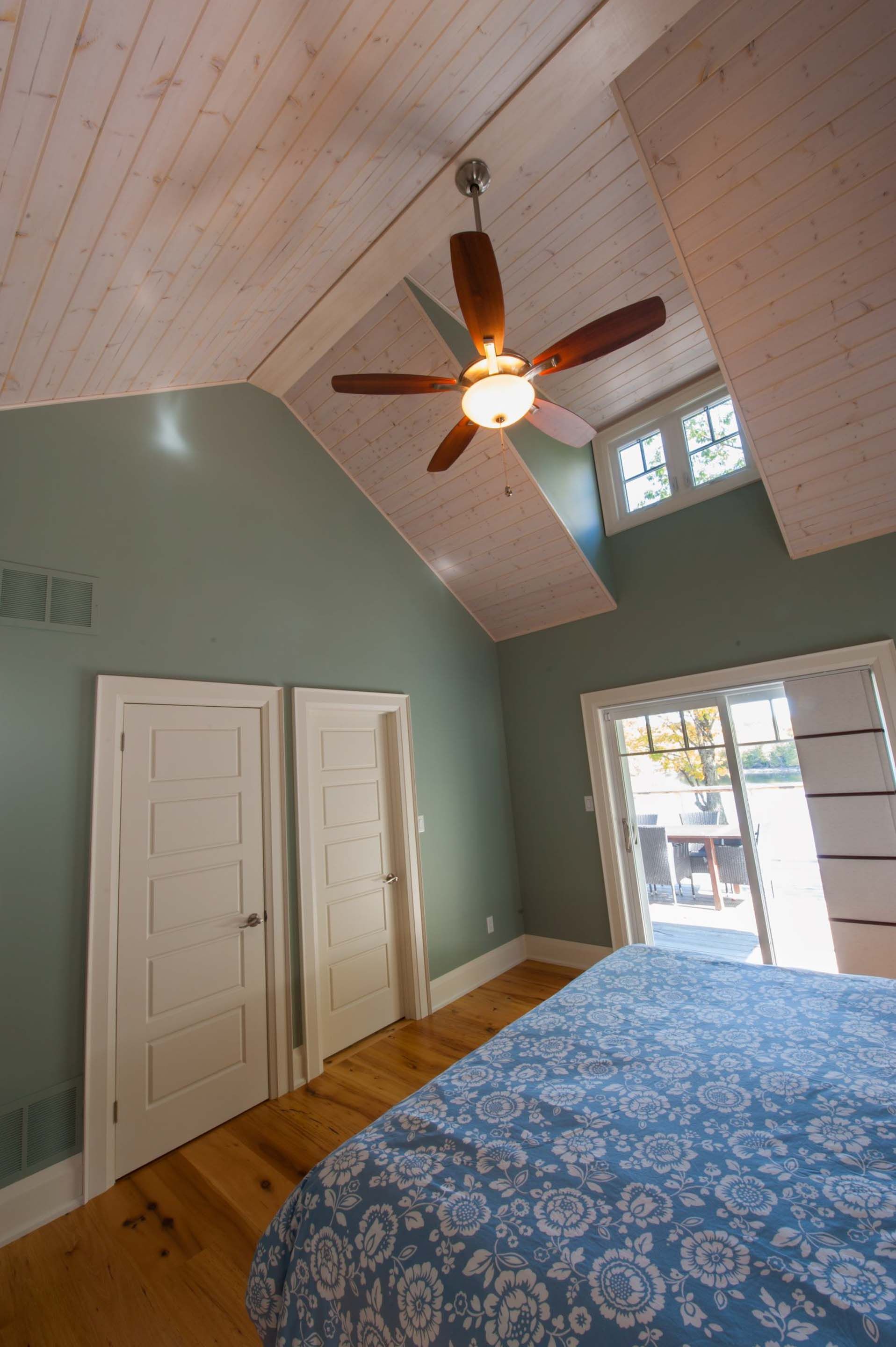 A bedroom with a bed and a ceiling fan