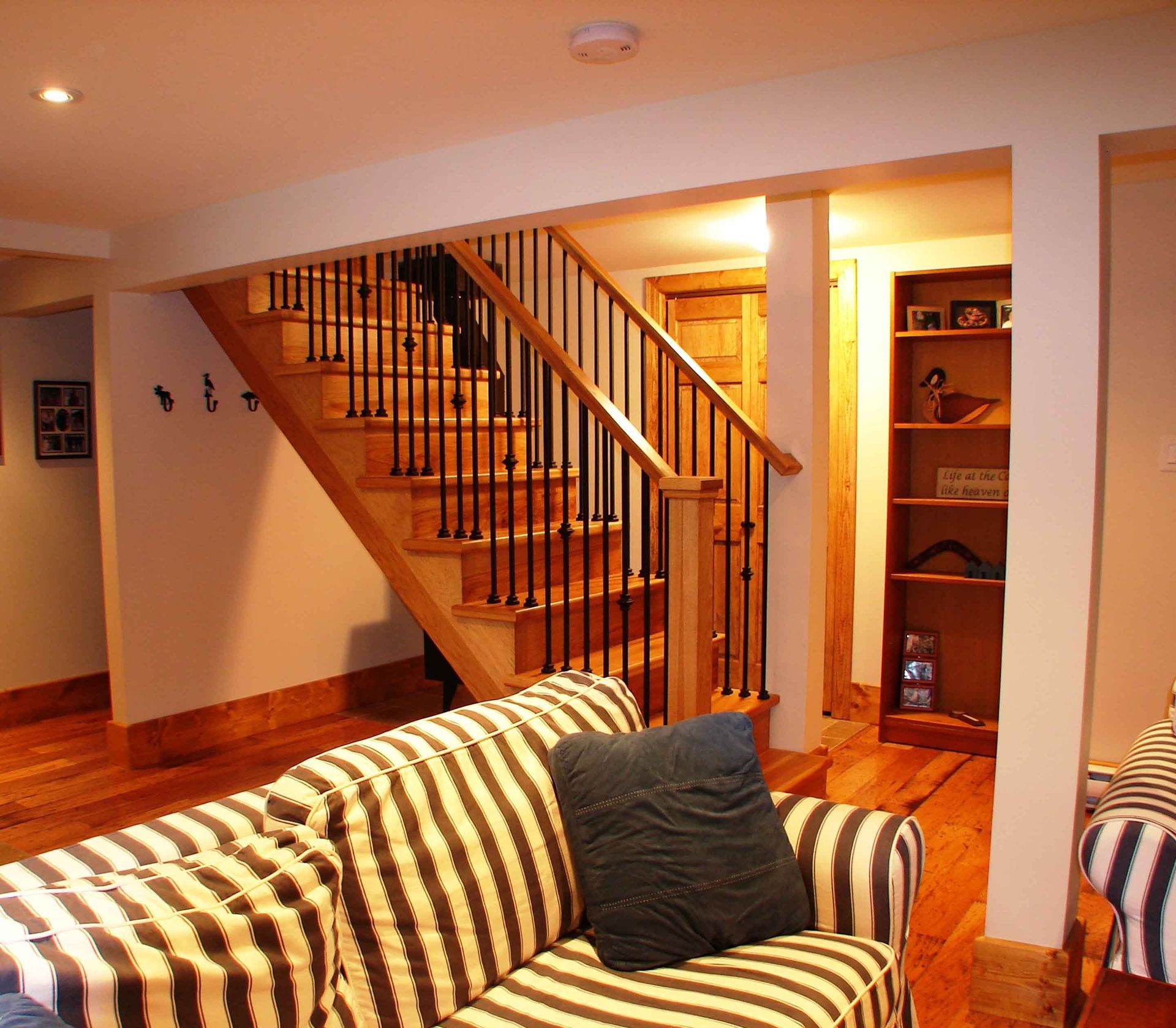 A living room with a striped couch and stairs
