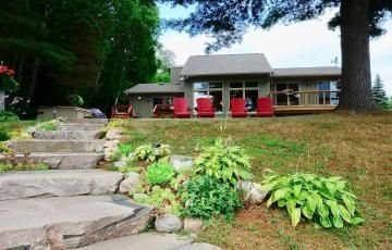 A house with stairs leading up to it and red chairs in front of it.