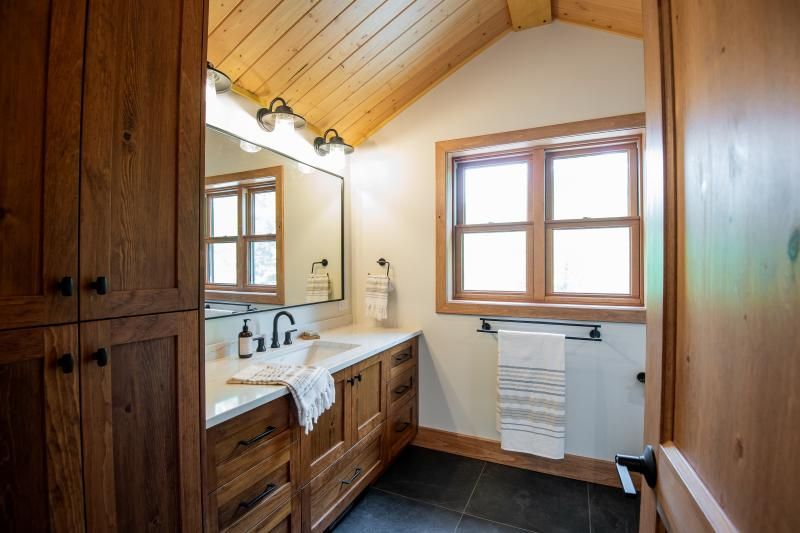 A bathroom with a sink , mirror and window.