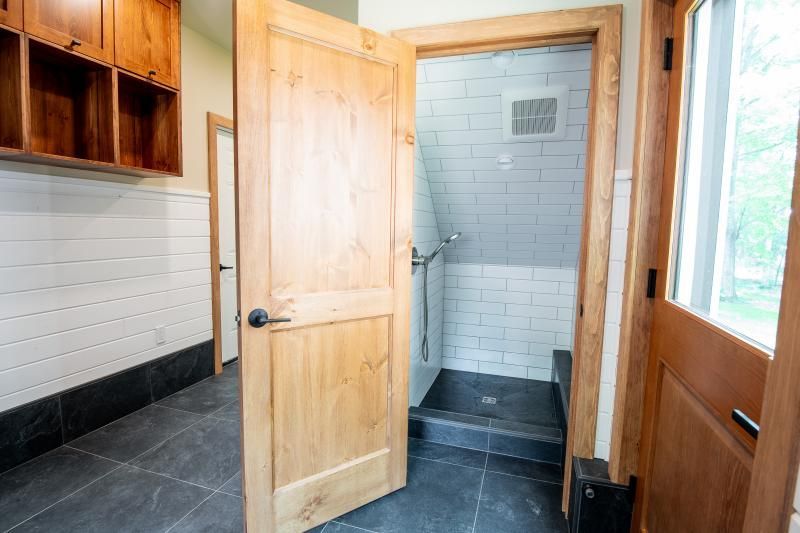 A bathroom with a walk in shower and a wooden door.