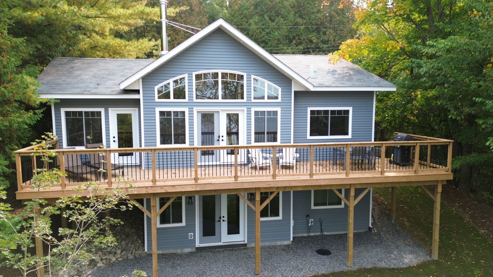 A house with a large deck is surrounded by trees