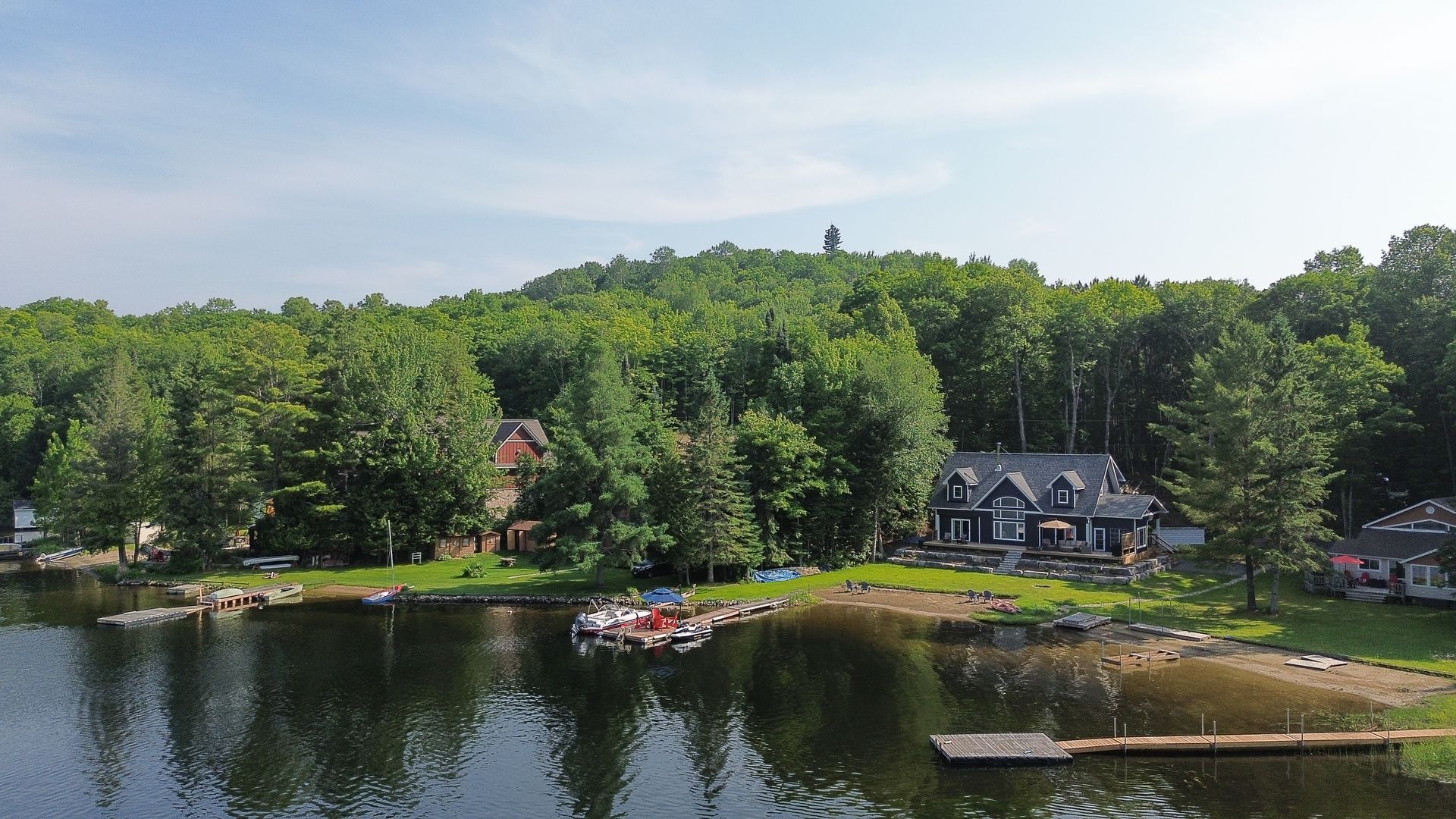 An aerial view of a lake with a house in the background surrounded by trees.