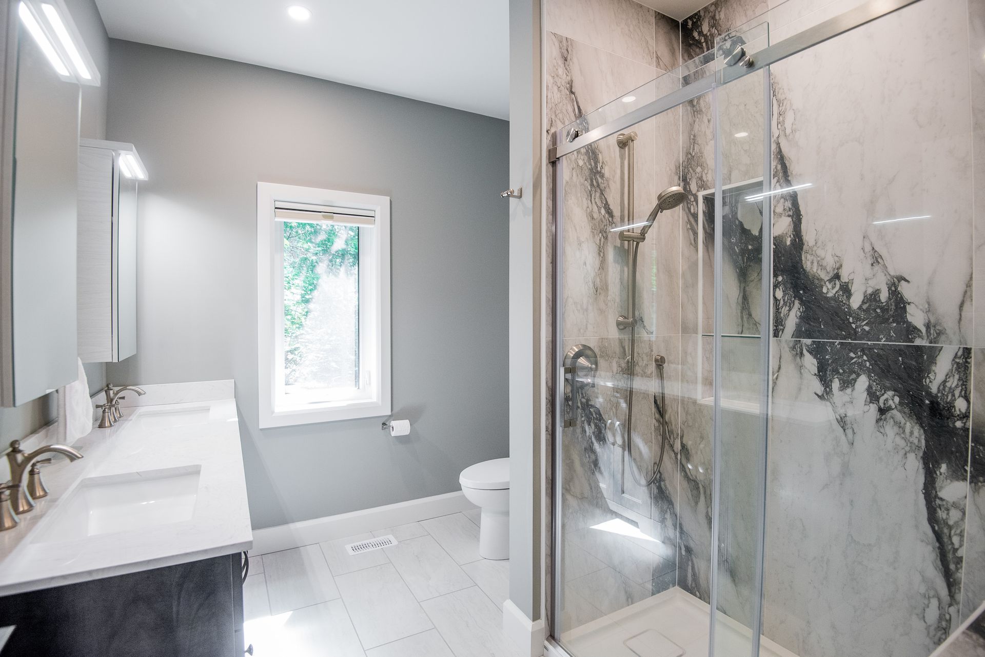 A bathroom with a walk in shower , sink , toilet and window.
