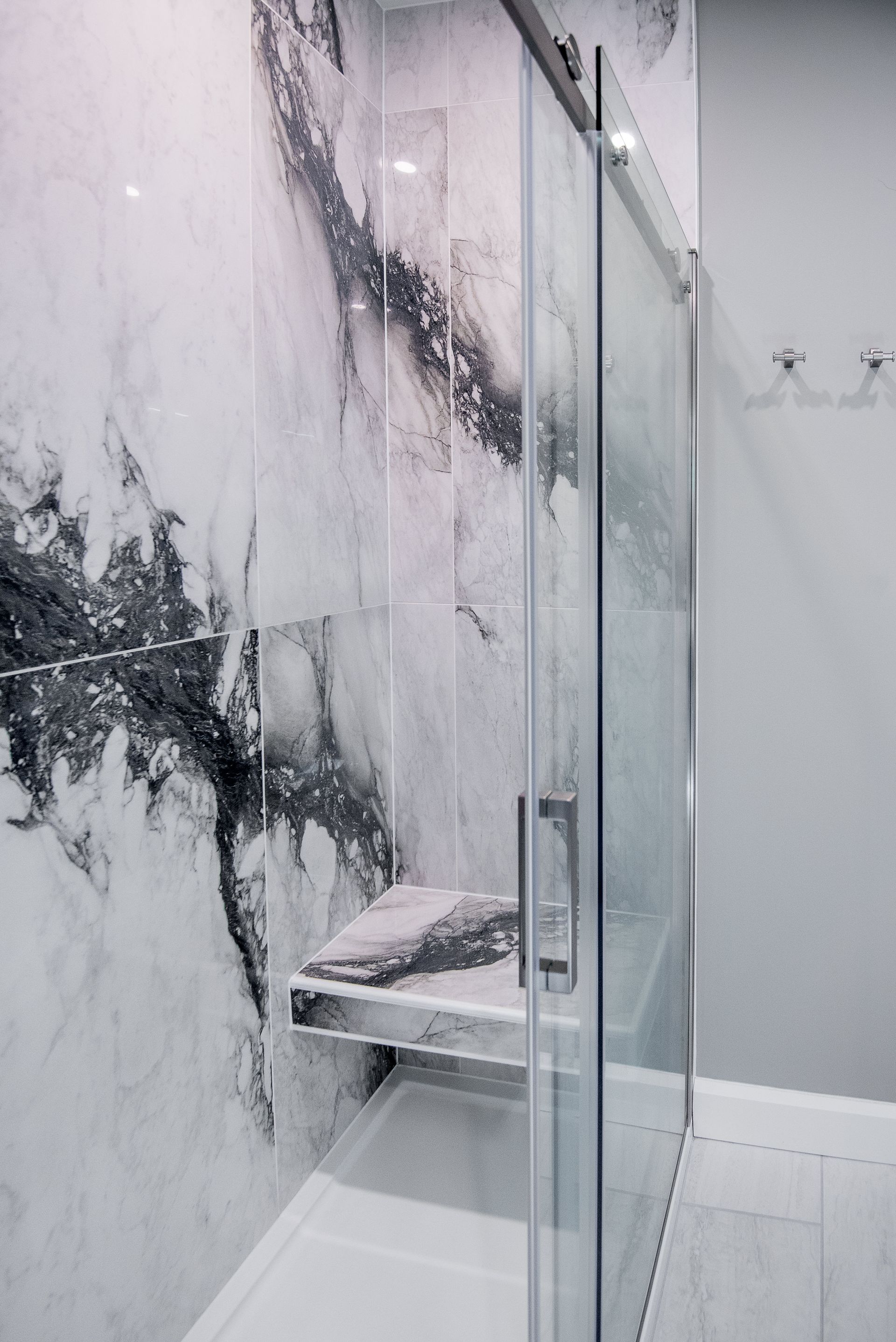 A bathroom with a walk in shower and a marble wall.