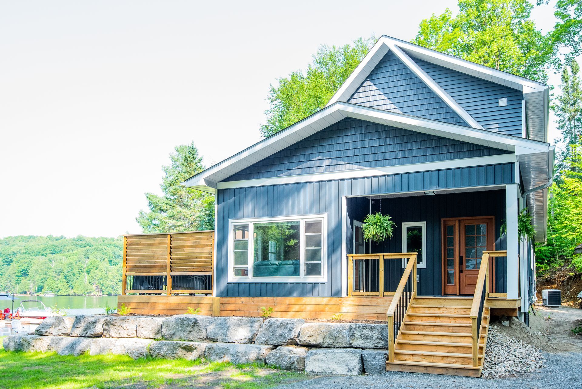A small blue house with stairs leading up to it is next to a lake.