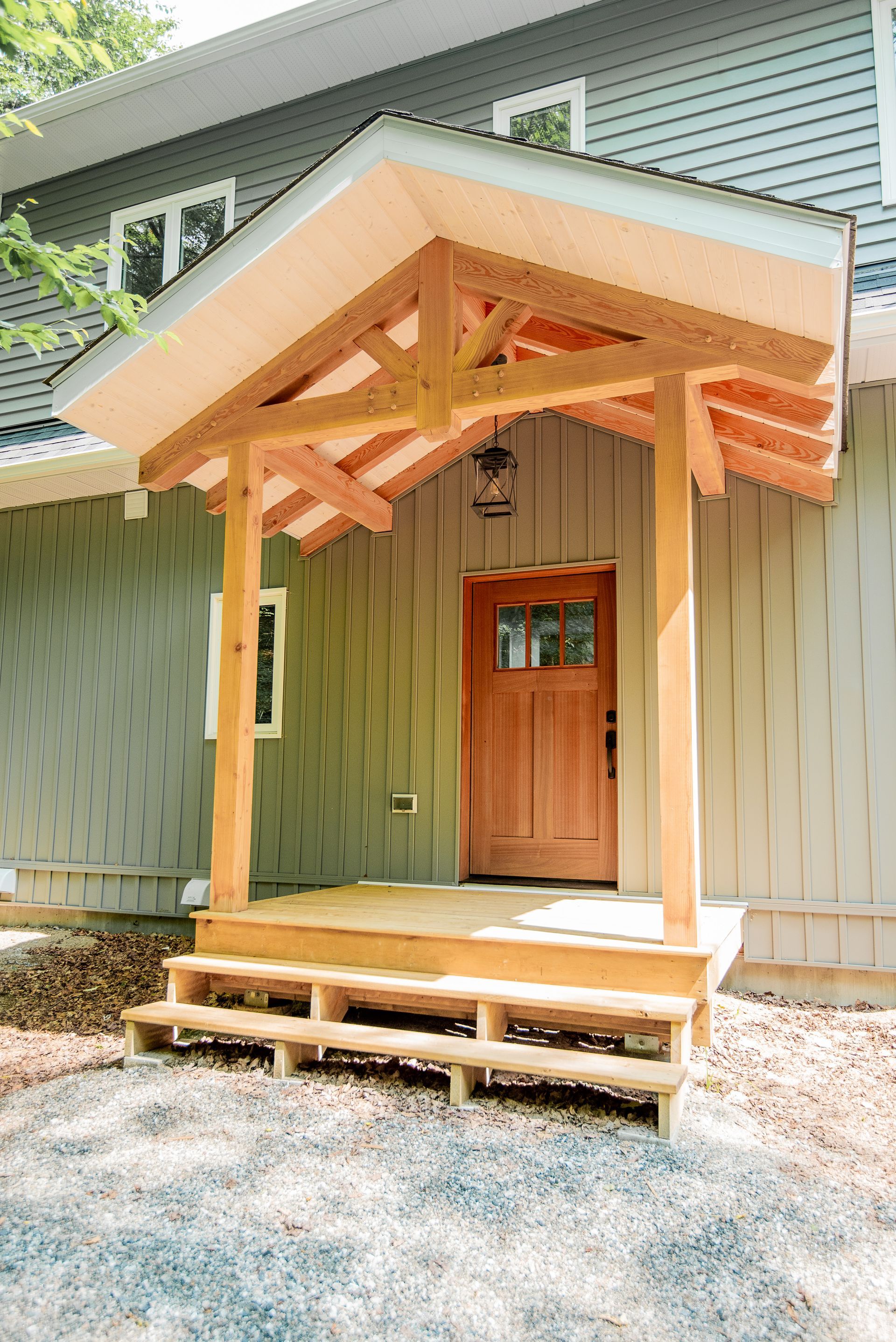 A wooden porch with a canopy over the door of a house.