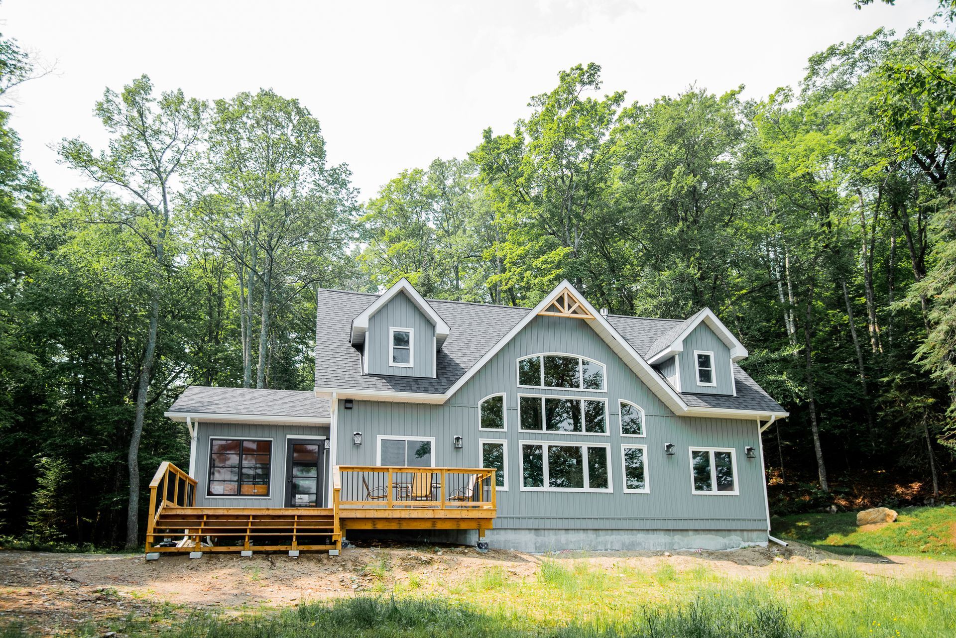 A large house with a large deck is surrounded by trees.
