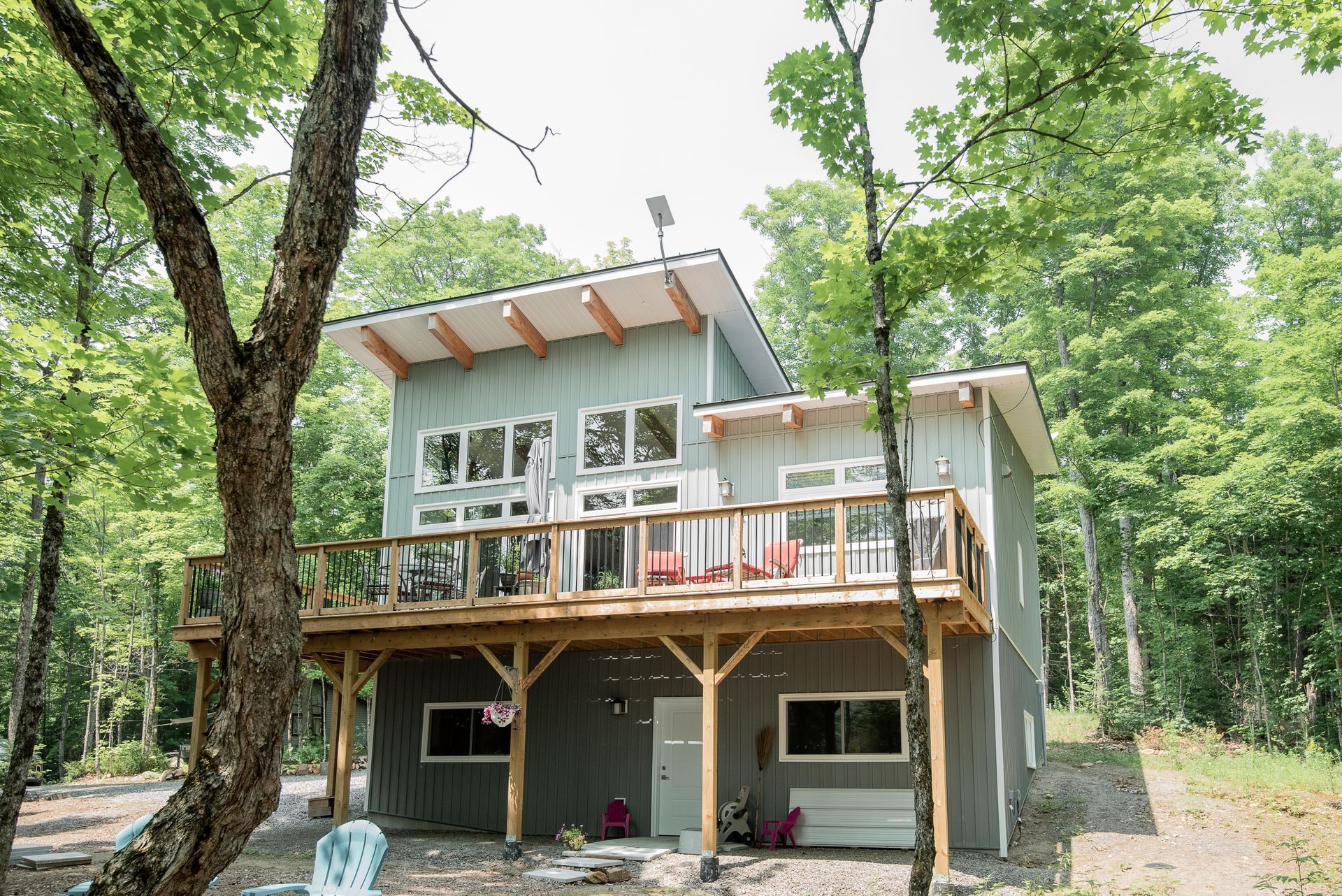 A large house with a large deck in the middle of a forest.