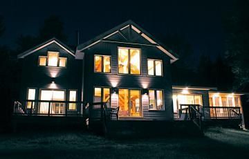 A large house with lots of windows is lit up at night.