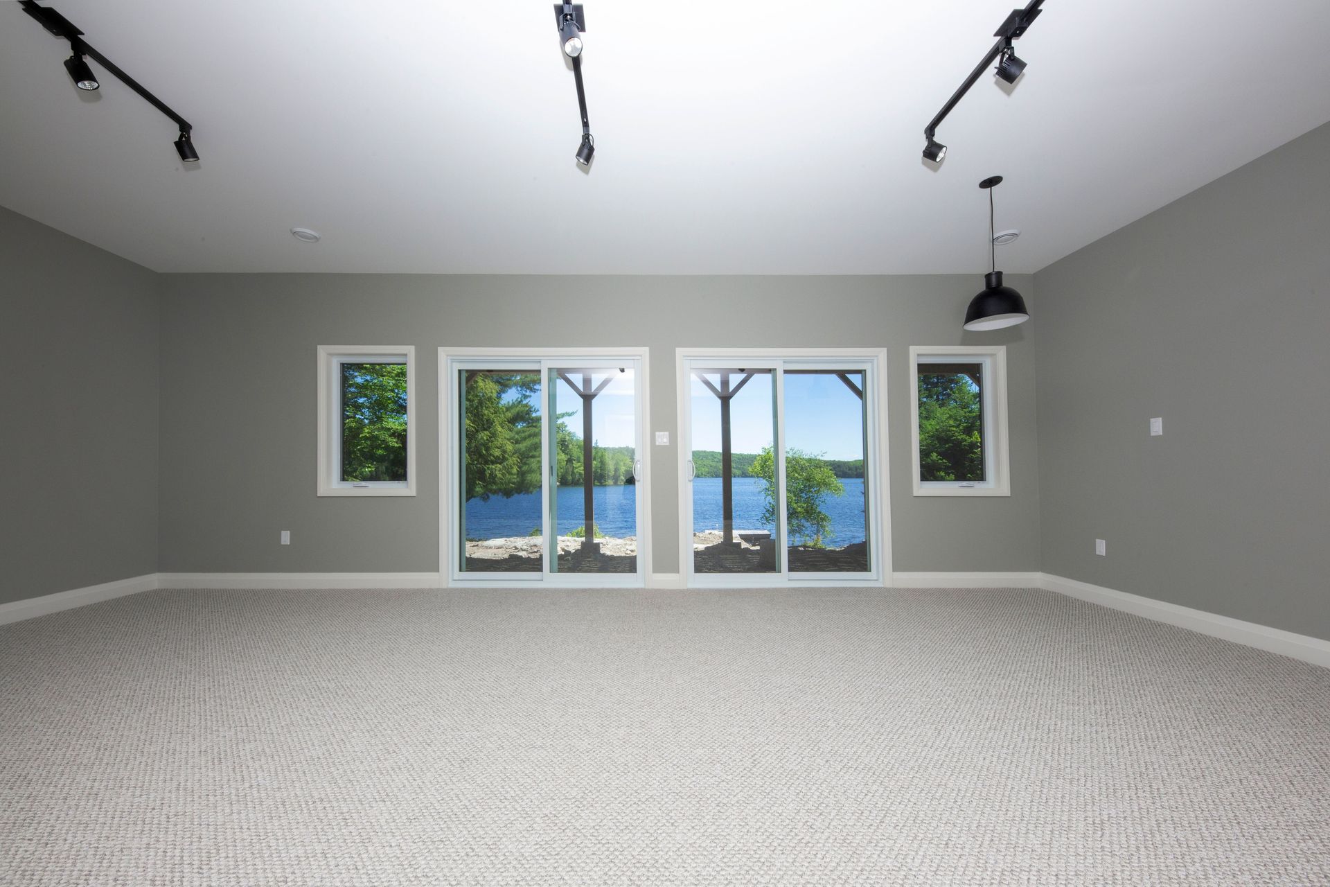An empty room with sliding glass doors leading to a lake