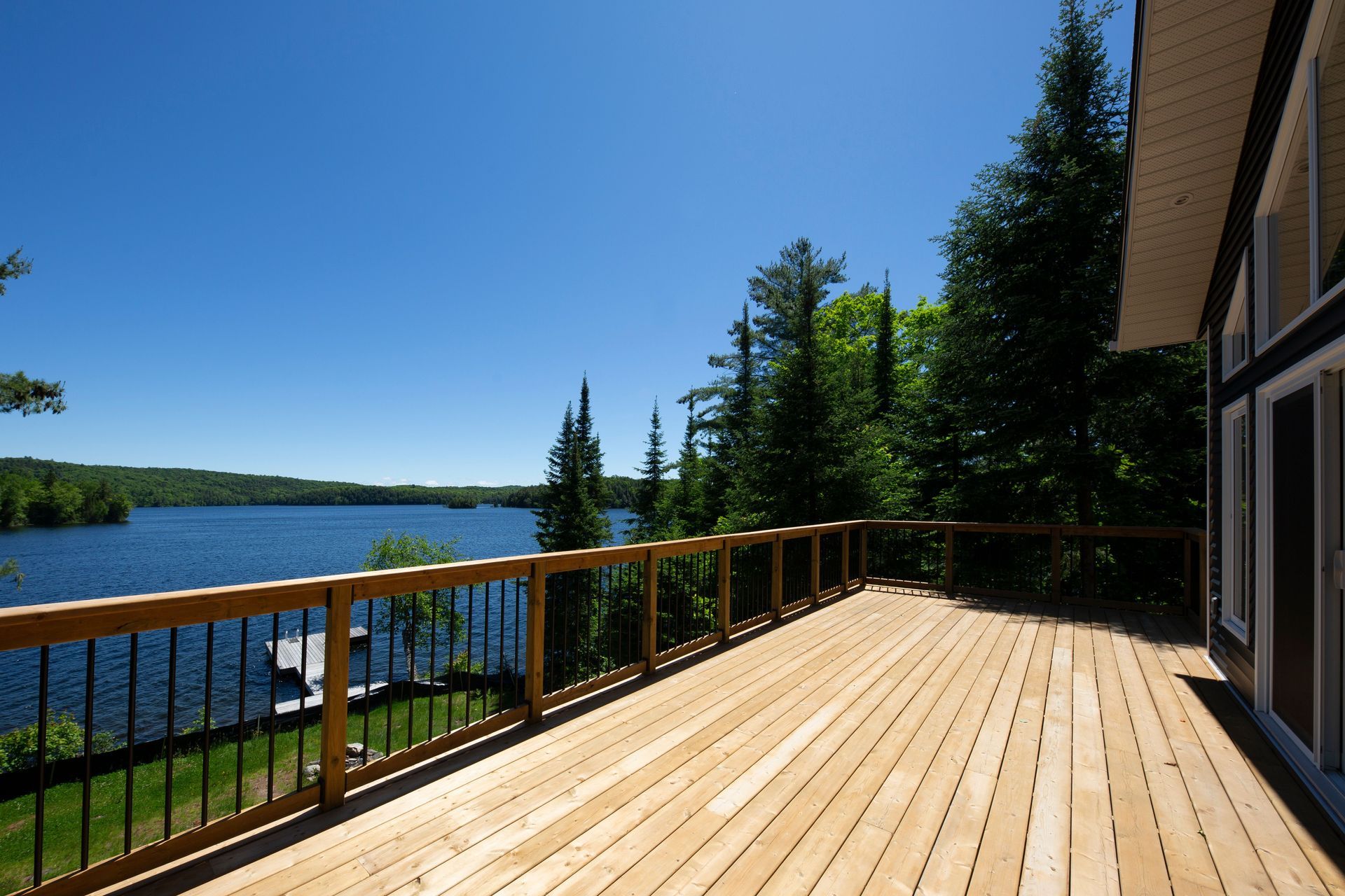 A large wooden deck overlooking a lake with trees in the background