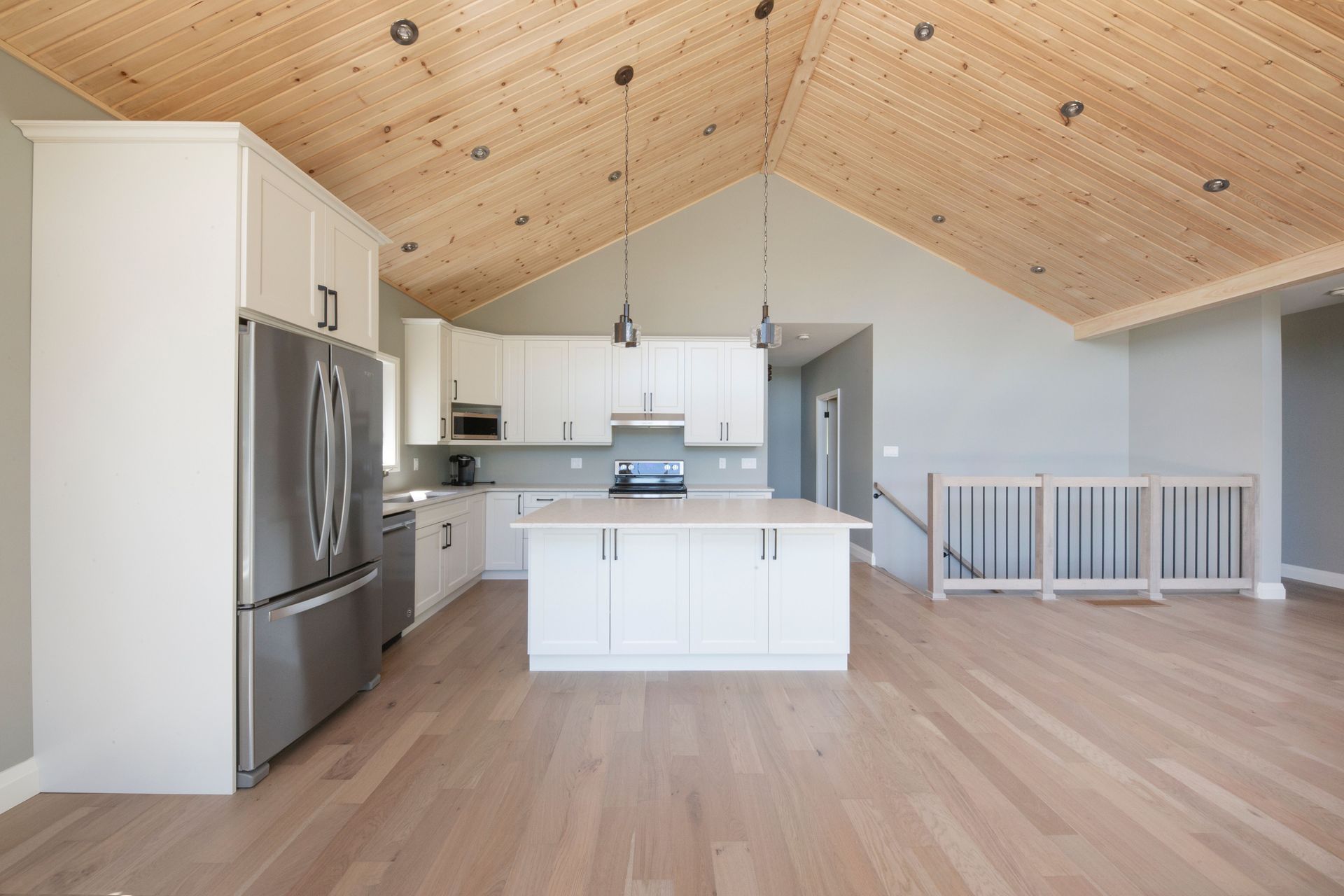 A kitchen with white cabinets and a wooden ceiling