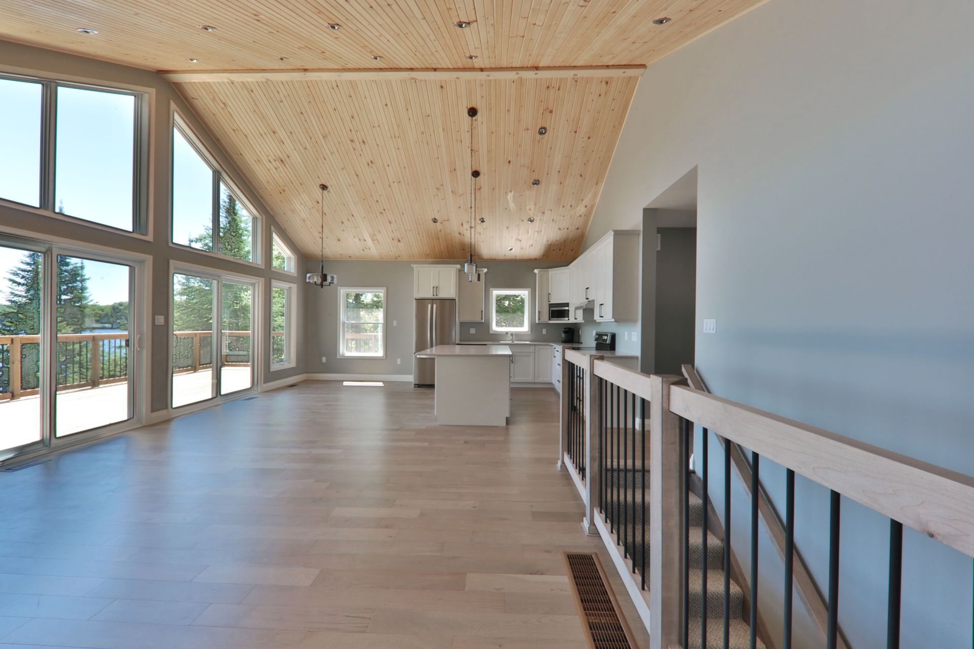 A large empty house with a wooden ceiling and lots of windows.